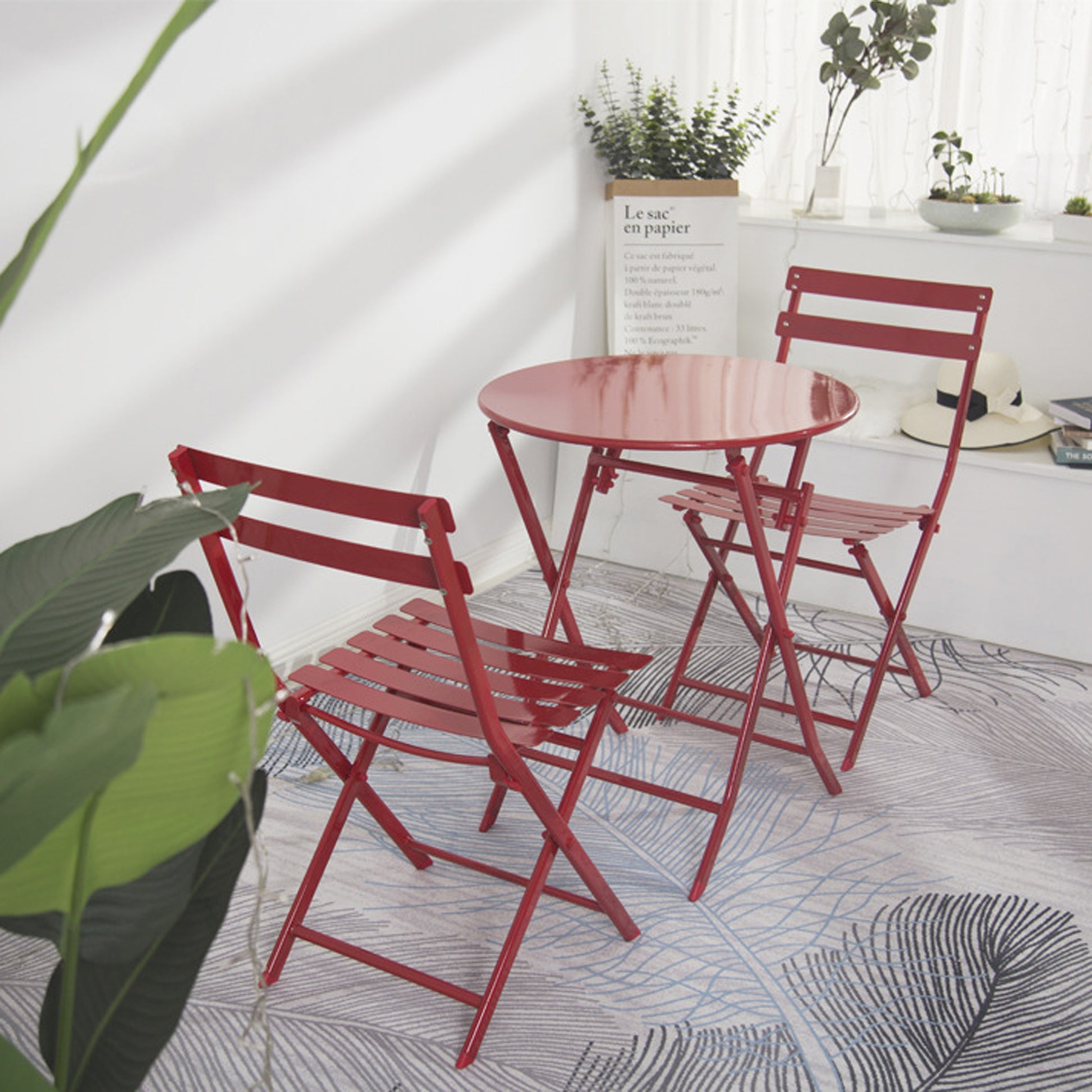 Red metal bistro set with round table and two chairs for outdoor dining