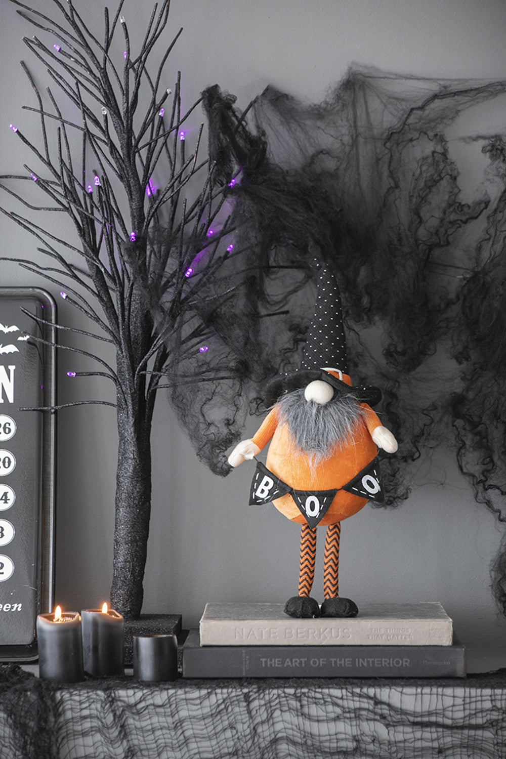 Orange plush gnome with grey beard wearing a black polka dot hat and holding a BOO banner