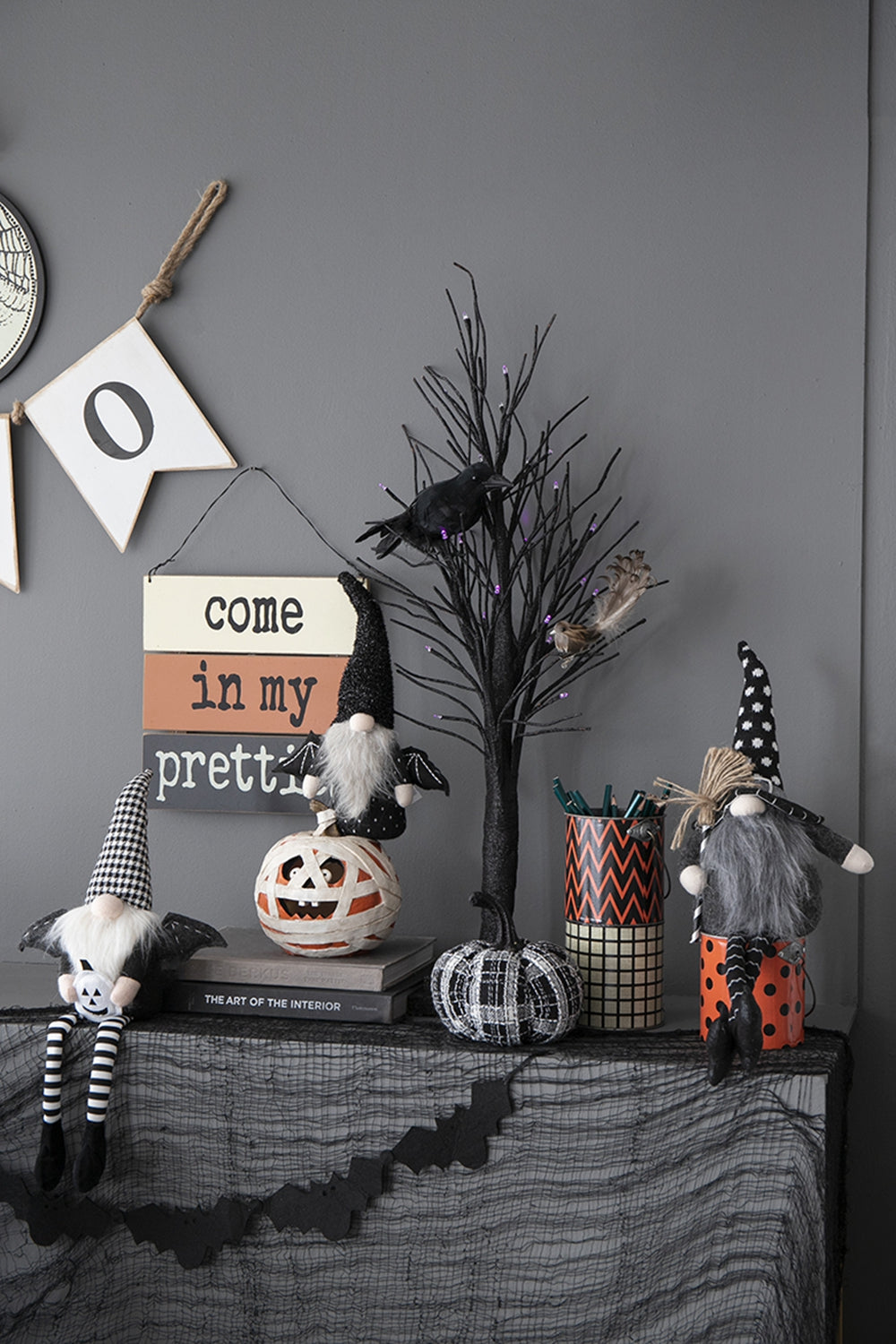Halloween gnome with black and white checkered hat holding a mini pumpkin