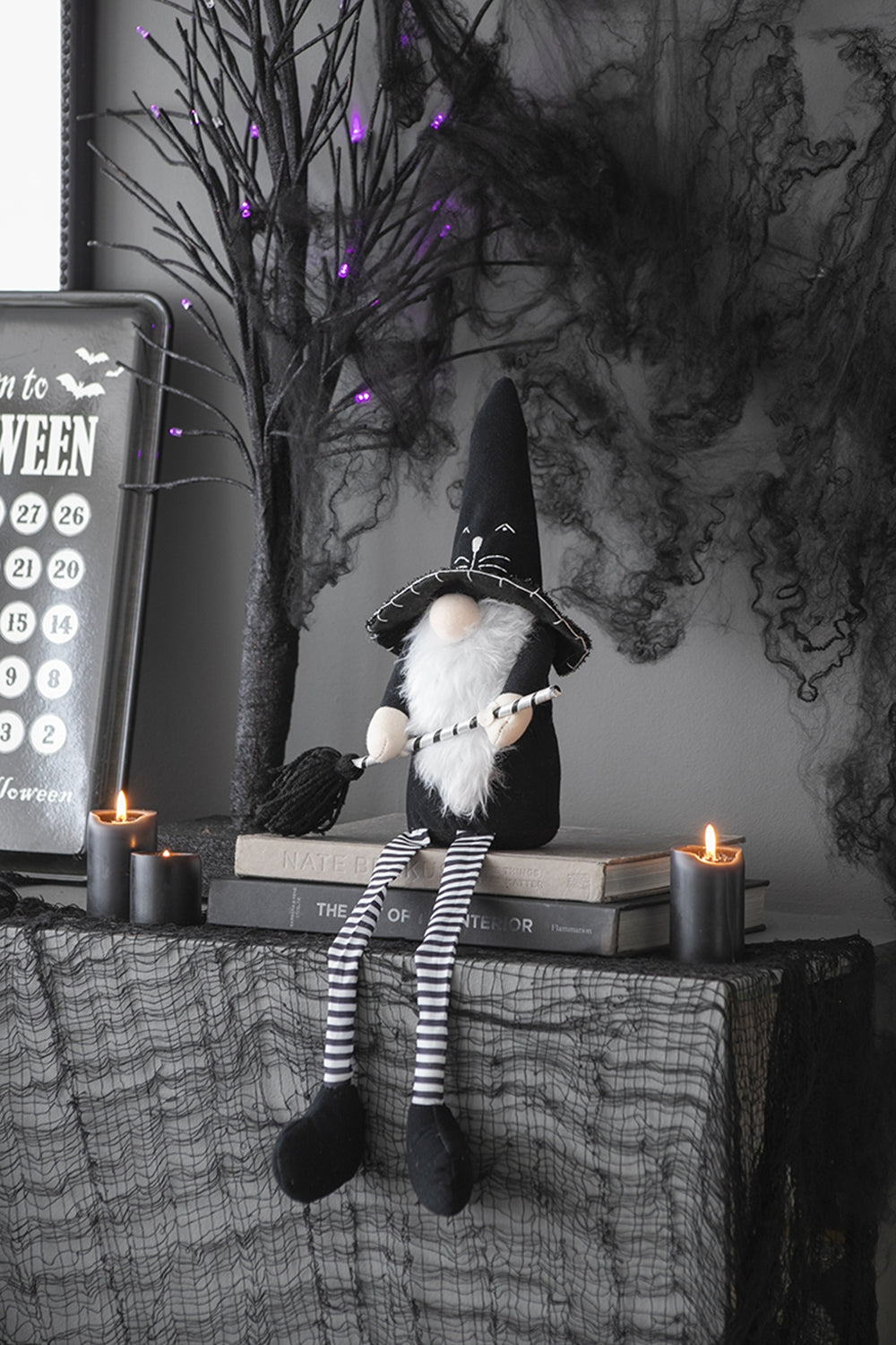 Halloween gnome with black witch hat and striped legs holding a broom