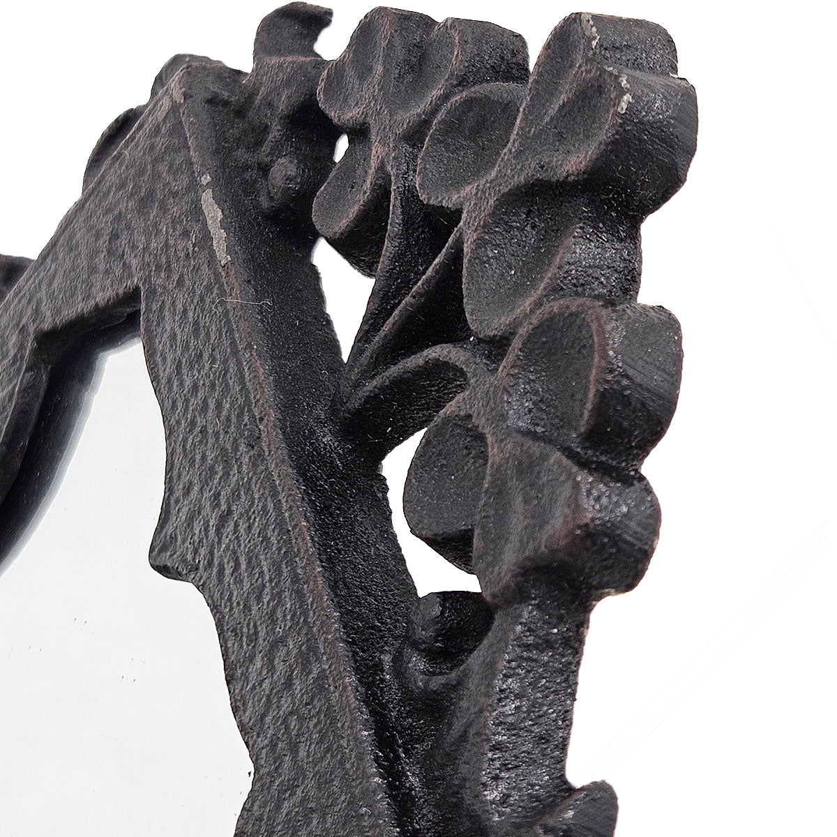 Closeup of black ornate cast iron mirror frame with floral details