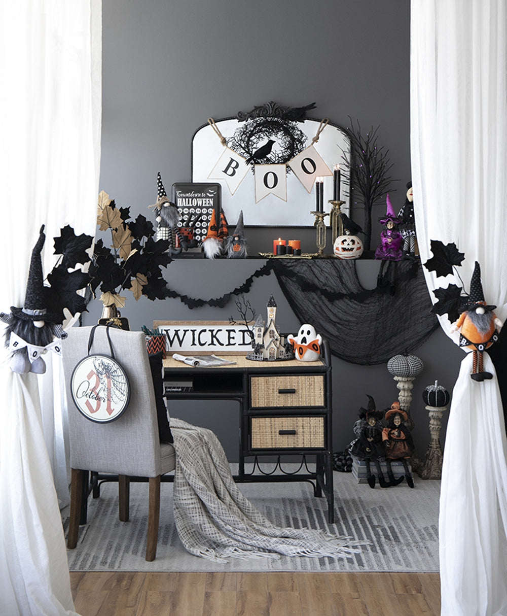 Halloween gnome with witch hat and black cloak hanging on white curtain