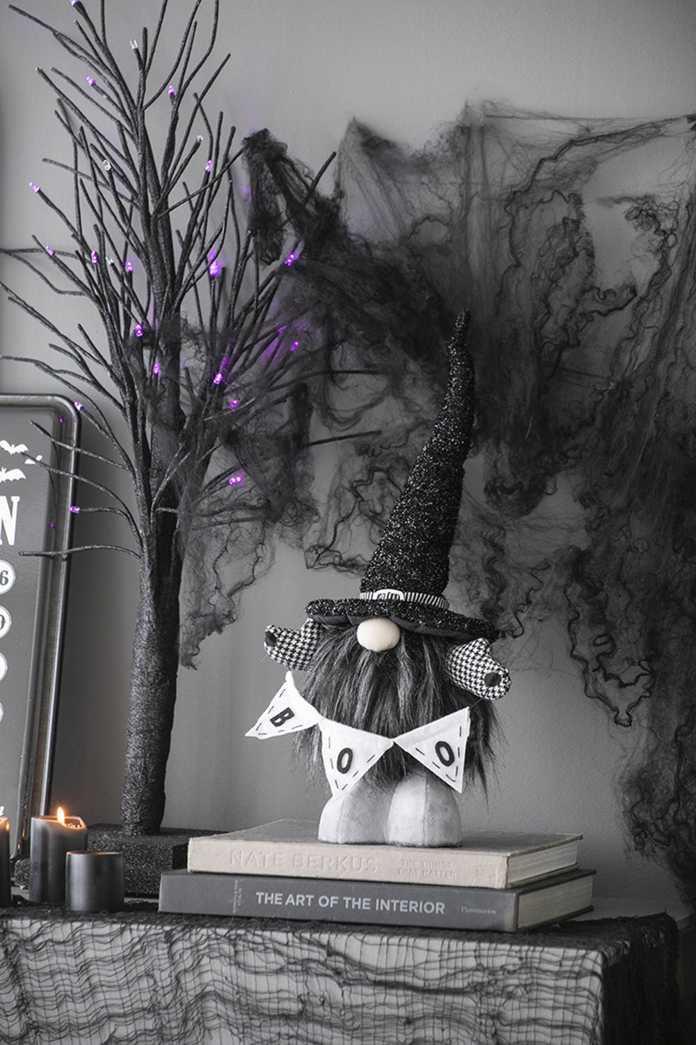Halloween gnome with sparkling witch hat and BOO banner on books