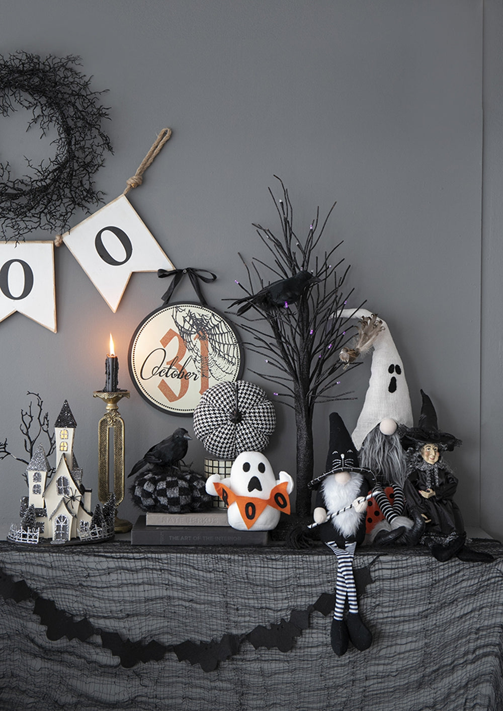 Halloween gnome with black witch hat and striped legs seated with a broom