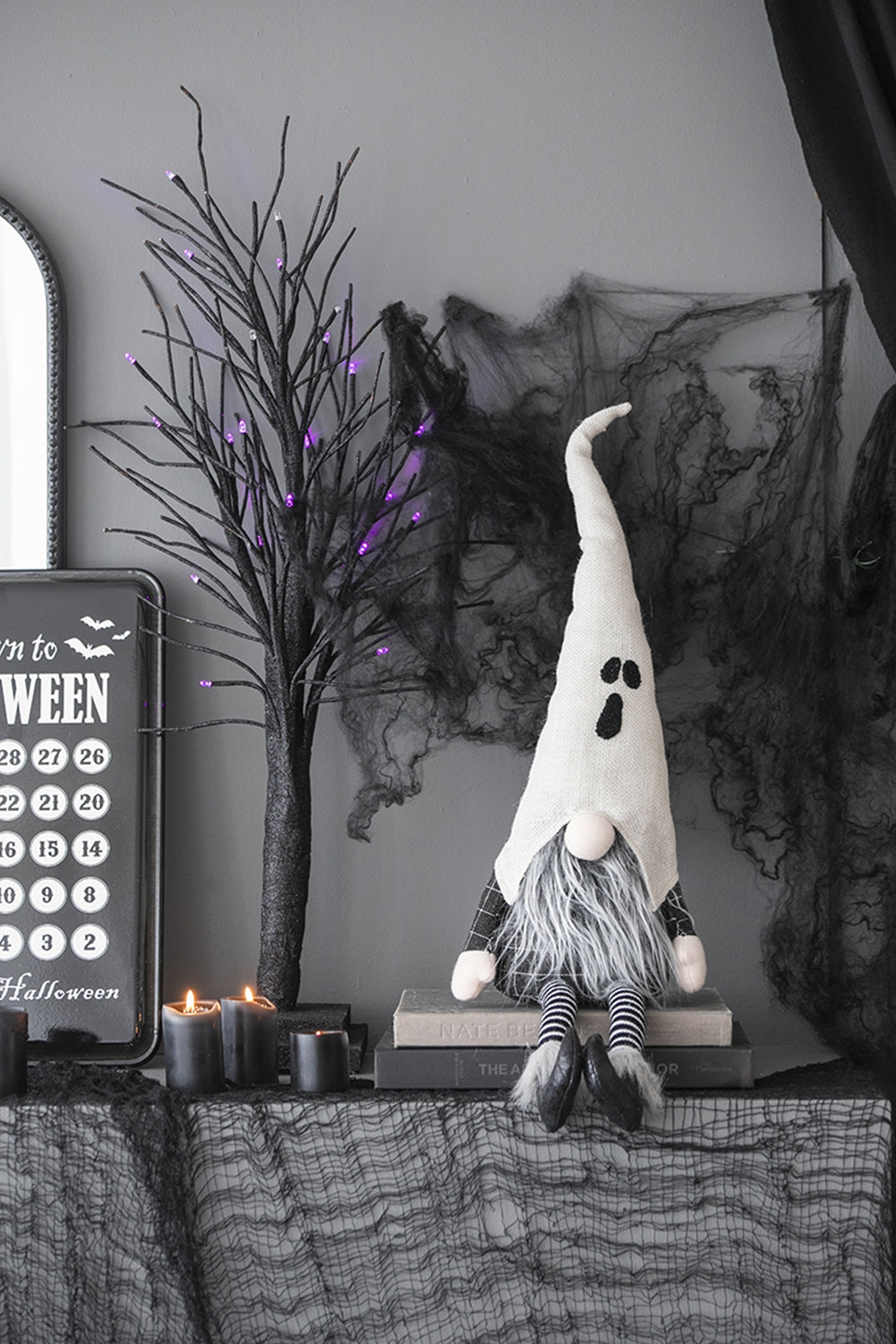 Spooky ghost gnome plush with white hat black face and striped socks for Halloween decor