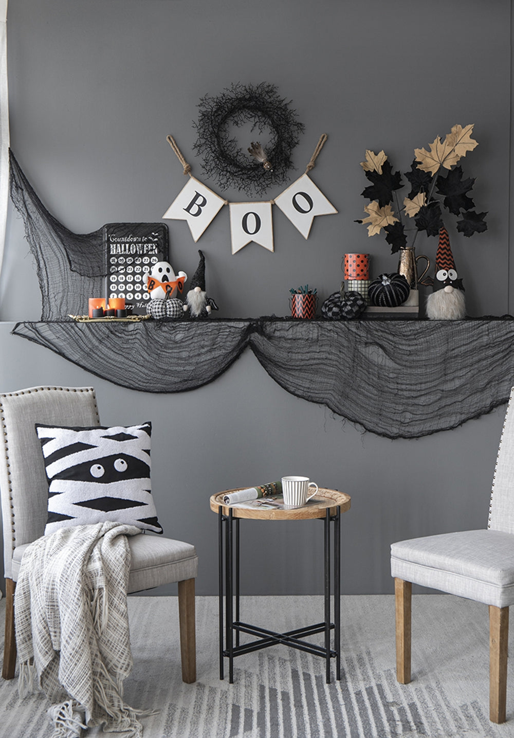 Black Halloween wreath with feather detail hangs above a BOO banner