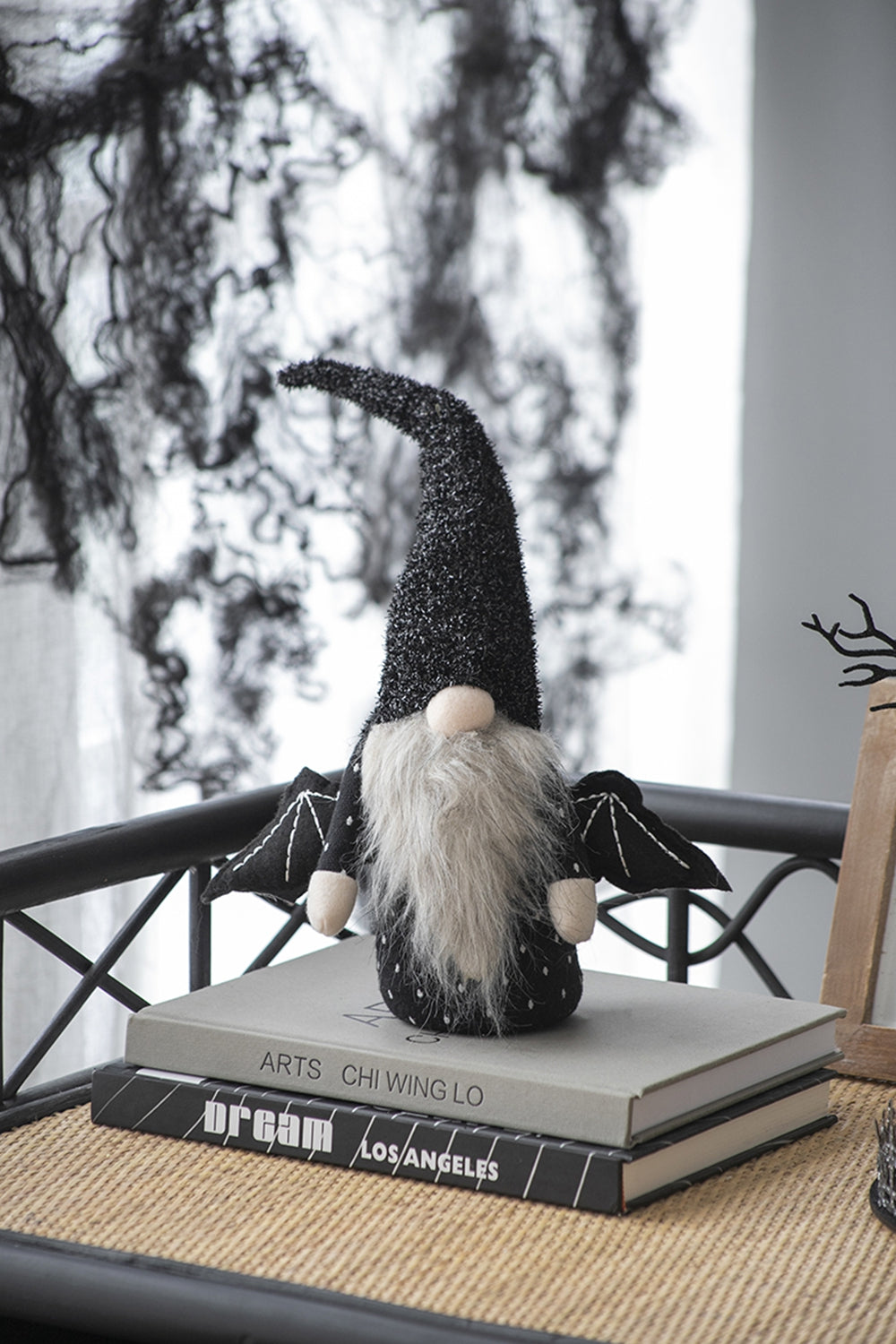 Sparkly black Halloween gnome with bat wings and long gray beard on books