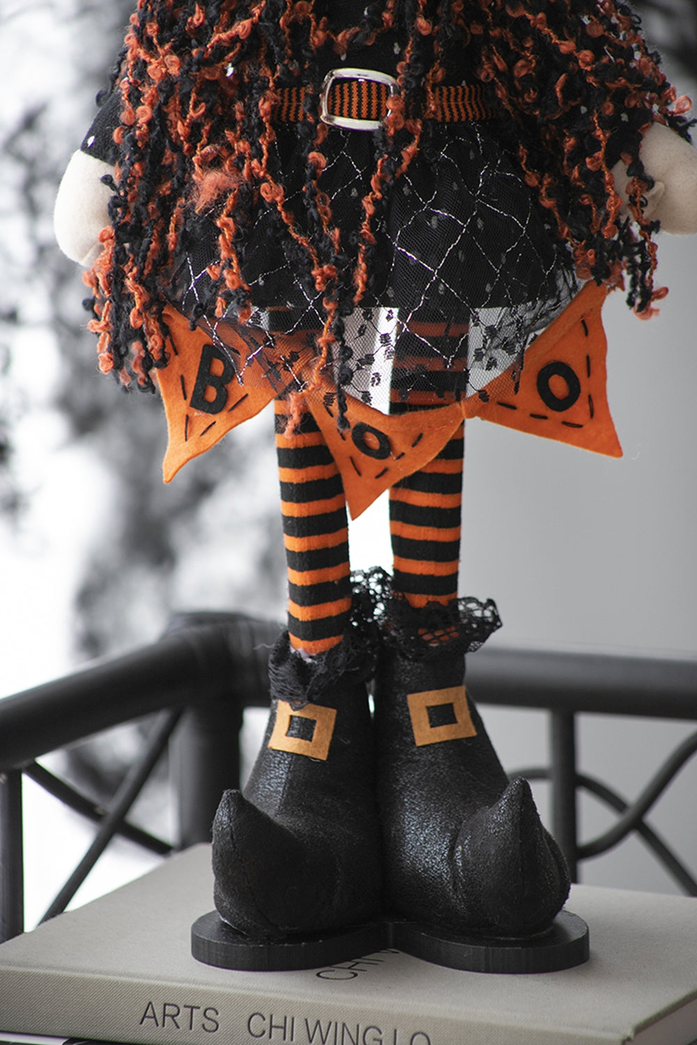 Plush Halloween witch with black and orange striped legs and BOO skirt banner
