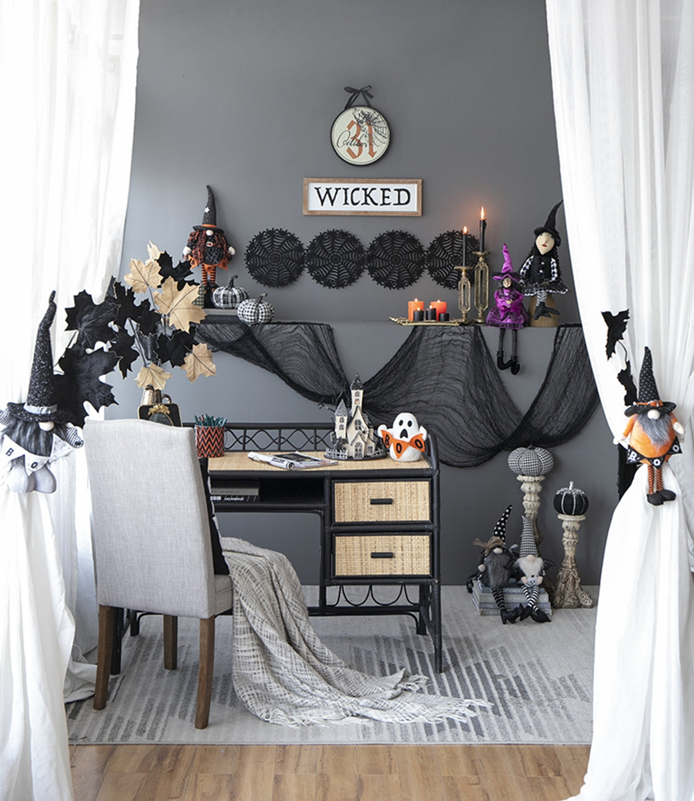 Halloween themed desk setup with witch figures and cobweb decorations