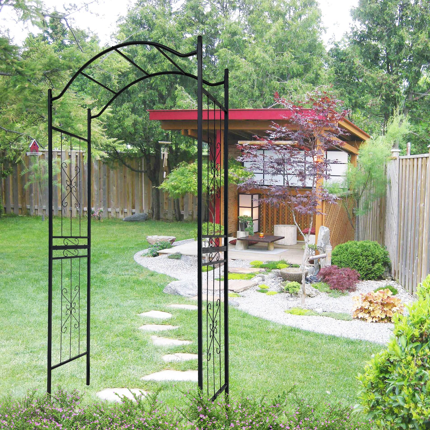 Black wrought iron garden arch with decorative scrollwork and a pathway
