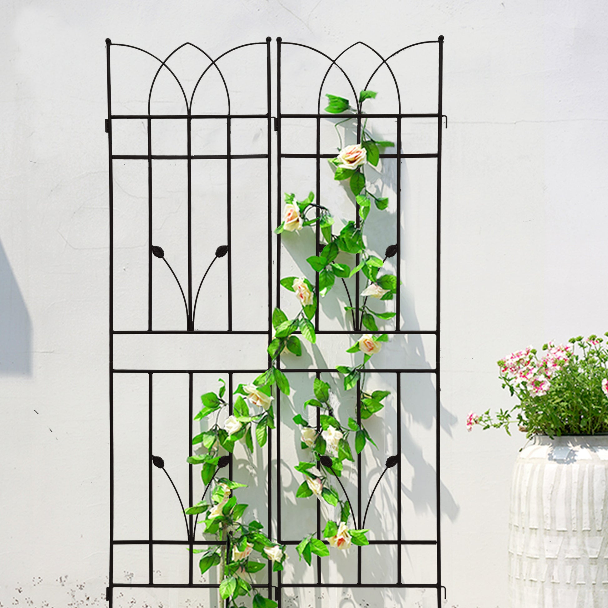 Tall black metal garden trellis with decorative arch top and climbing rose vine