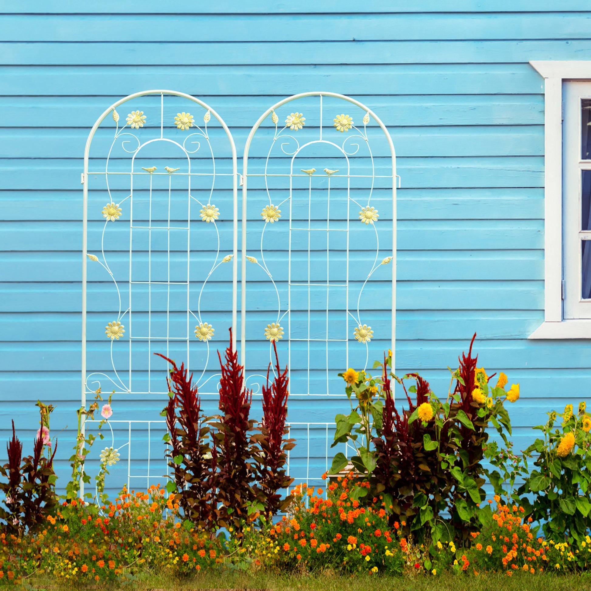 White metal garden trellis with floral and bird accents against blue siding