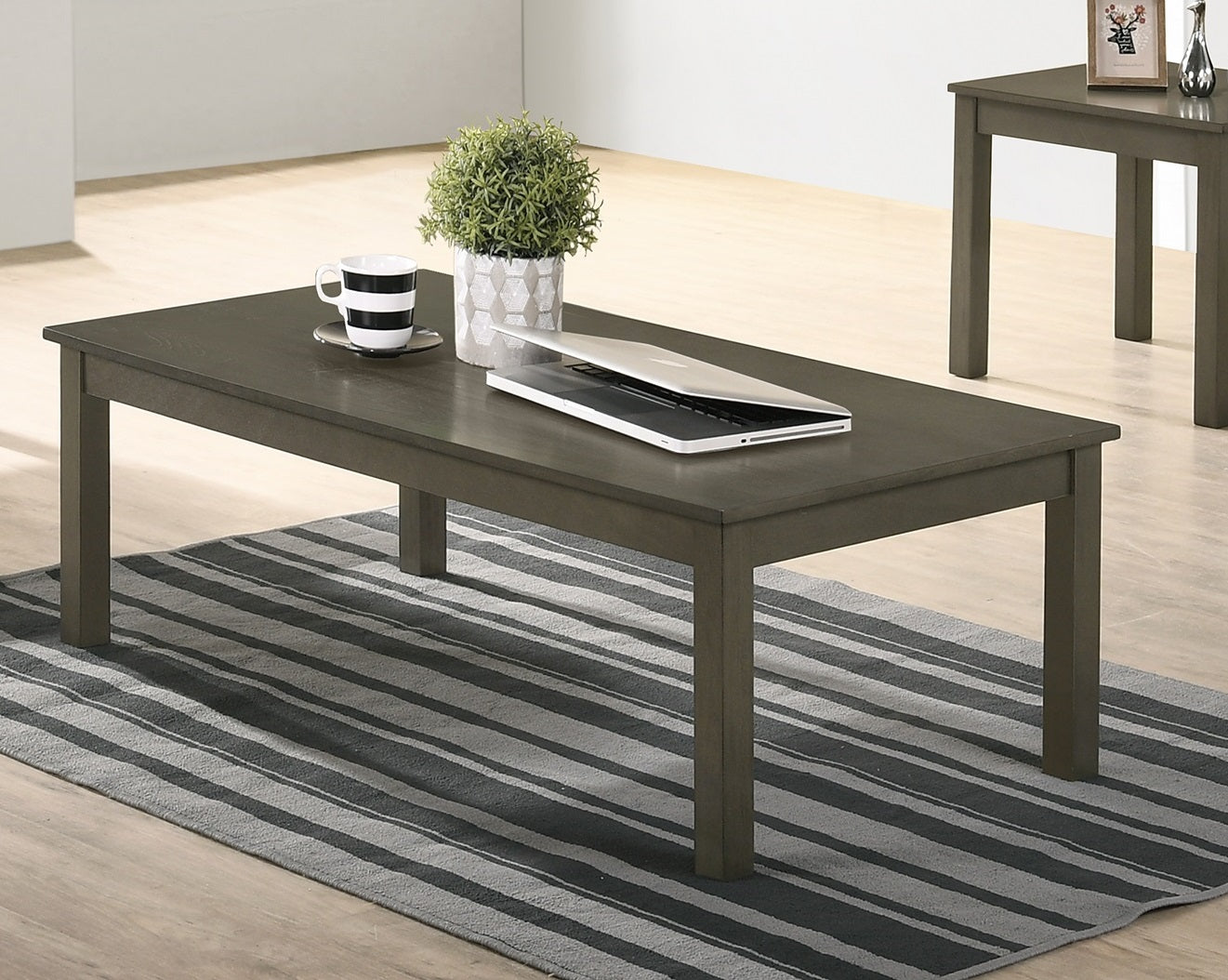 Dark grey rectangular coffee table with a laptop and plant
