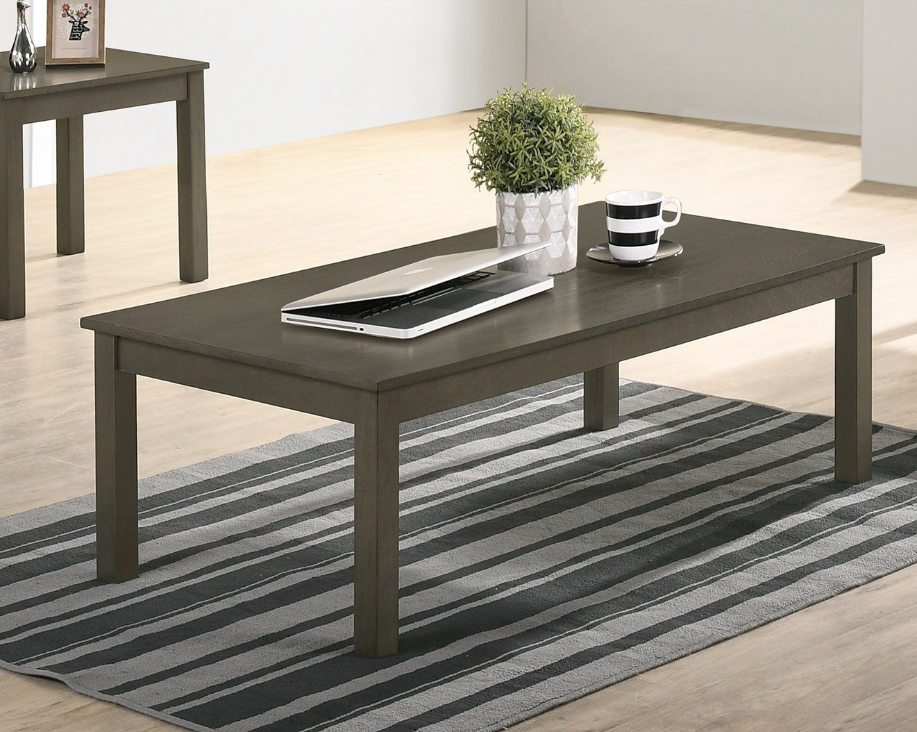 Dark gray wooden coffee table with laptop mug and plant