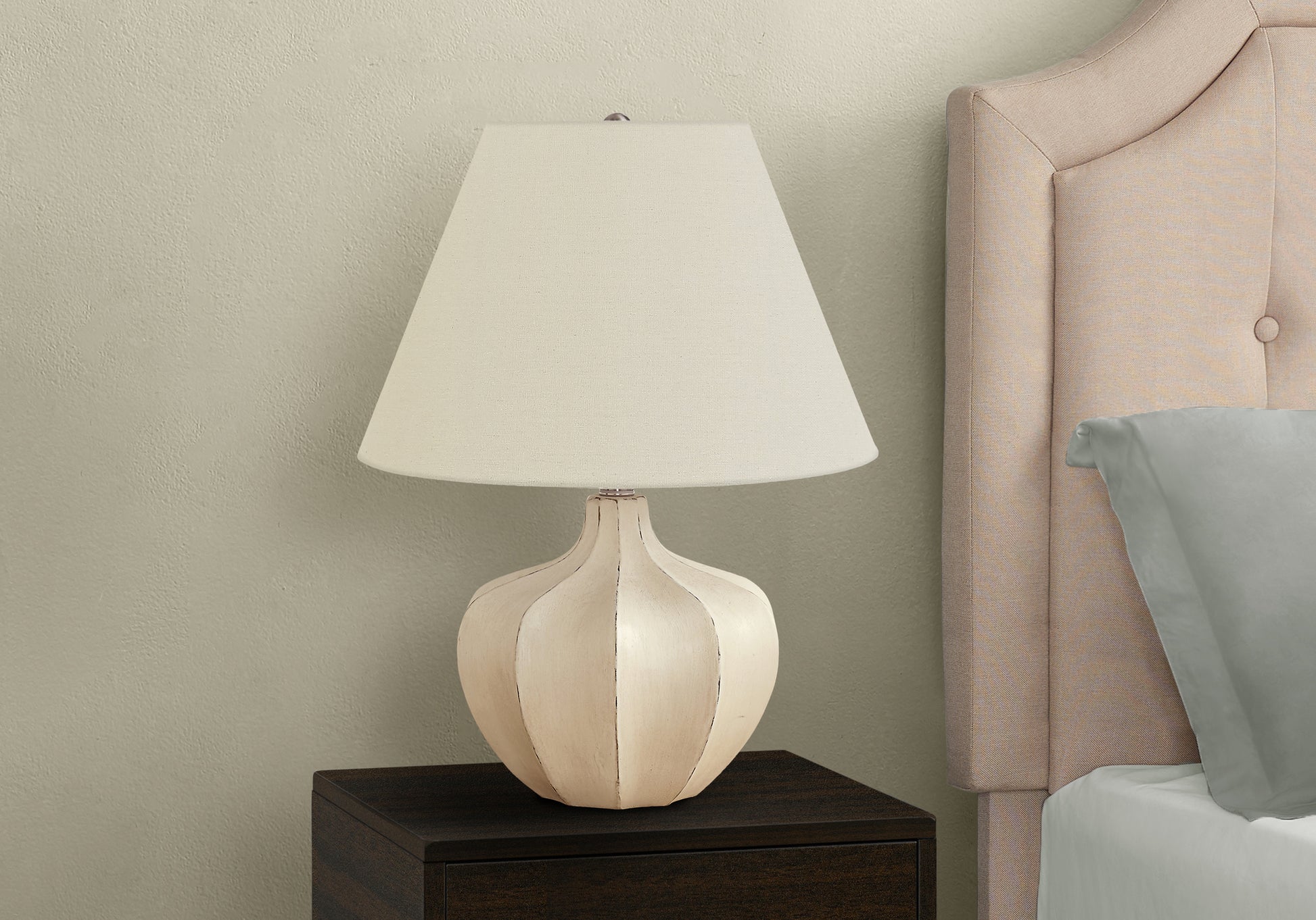 Offwhite ceramic table lamp with cream shade on dark wood nightstand