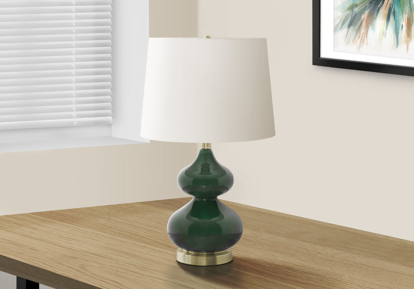 Dark green glass table lamp with a white drum shade and brass accents