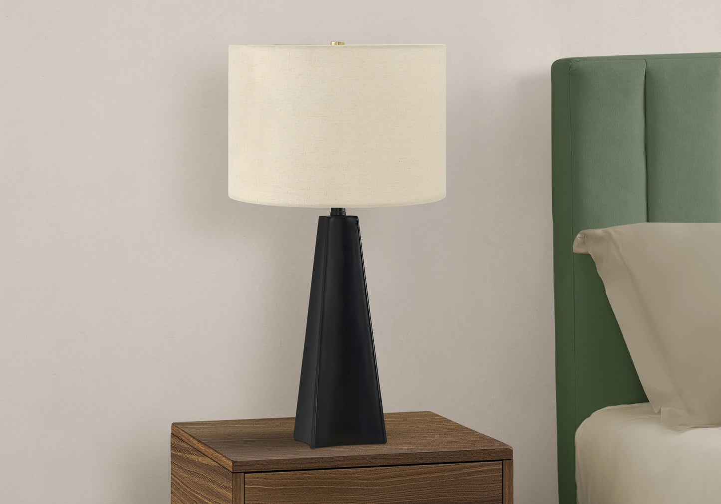 Black tapered base table lamp with cream linen shade on a wood nightstand