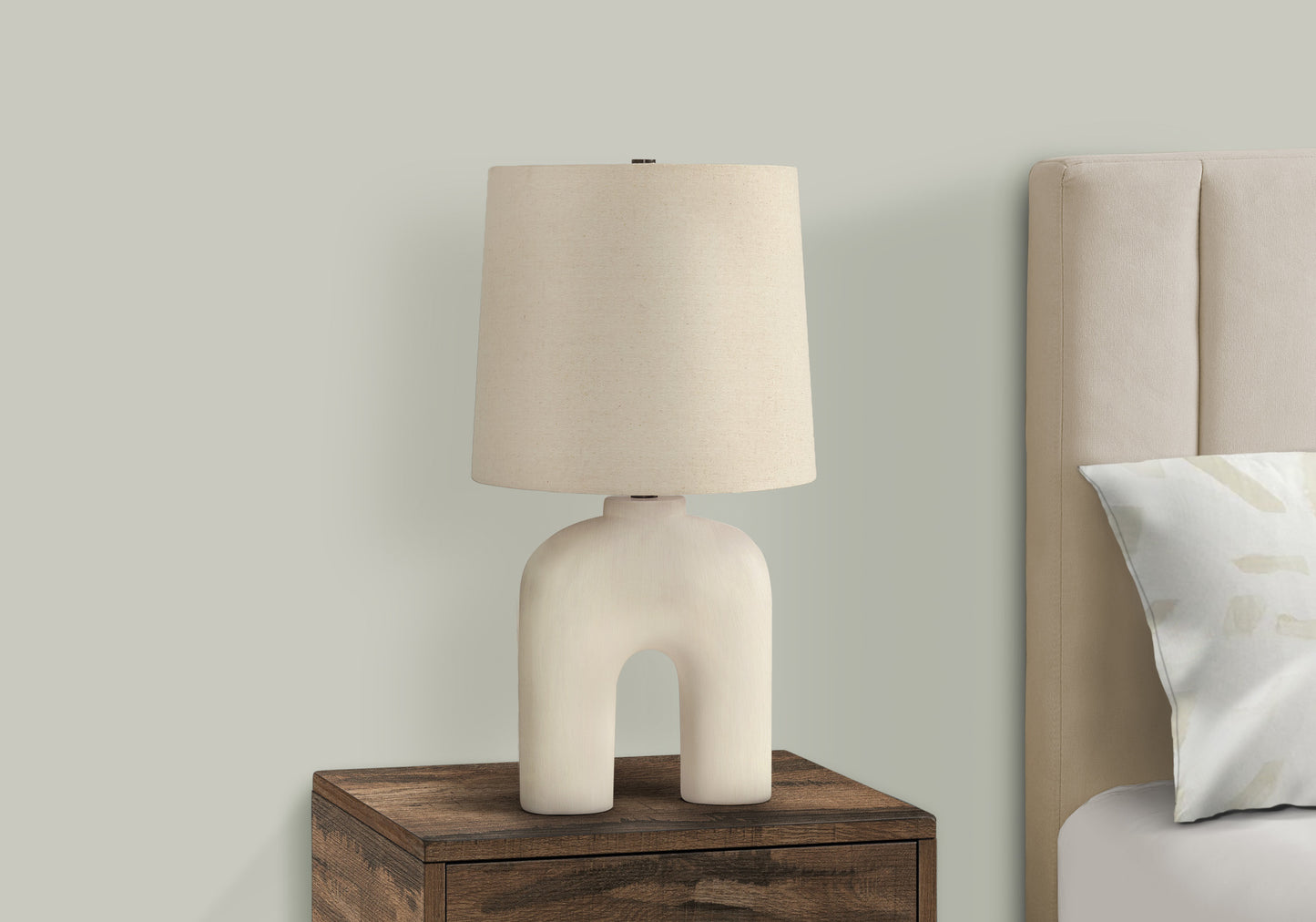 Cream ceramic arch table lamp with linen shade on wooden nightstand