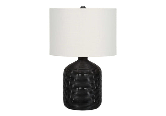 Woven black rattan base table lamp with white drum shade and natural texture