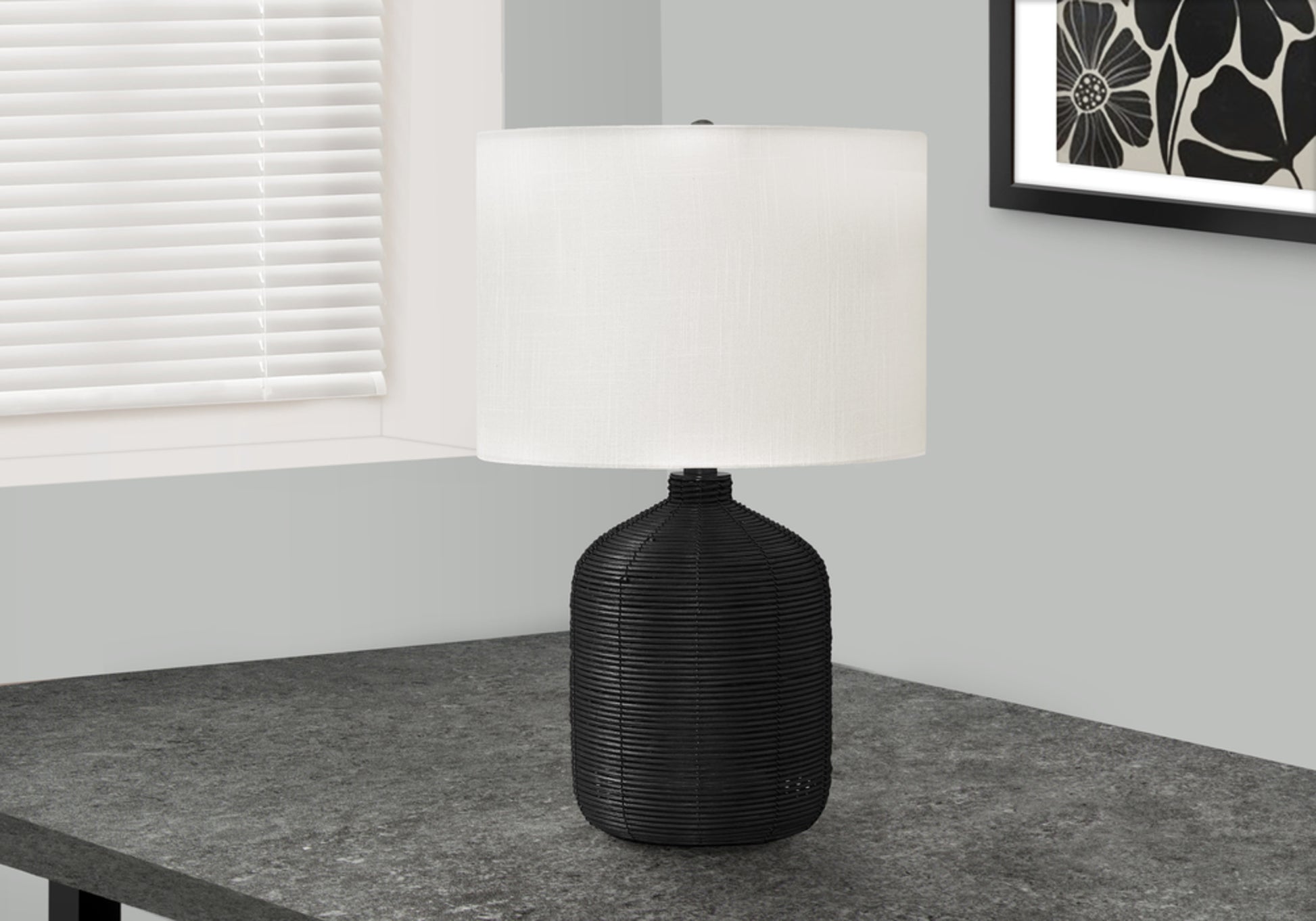 Woven black rattan table lamp with white drum shade and textured base