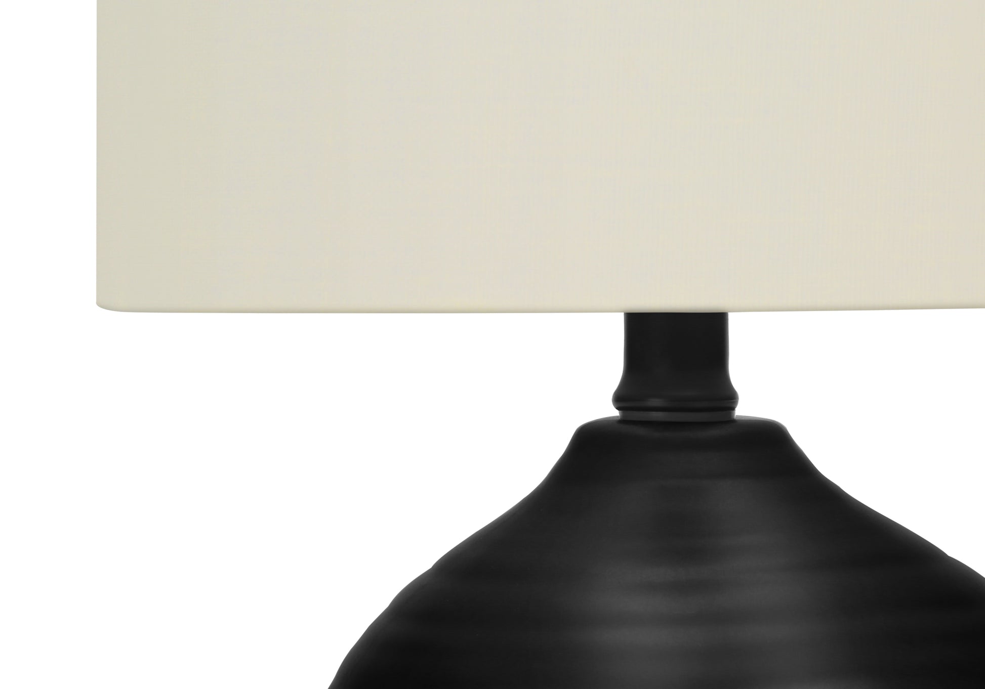 Closeup of black metal table lamp base with ivory shade