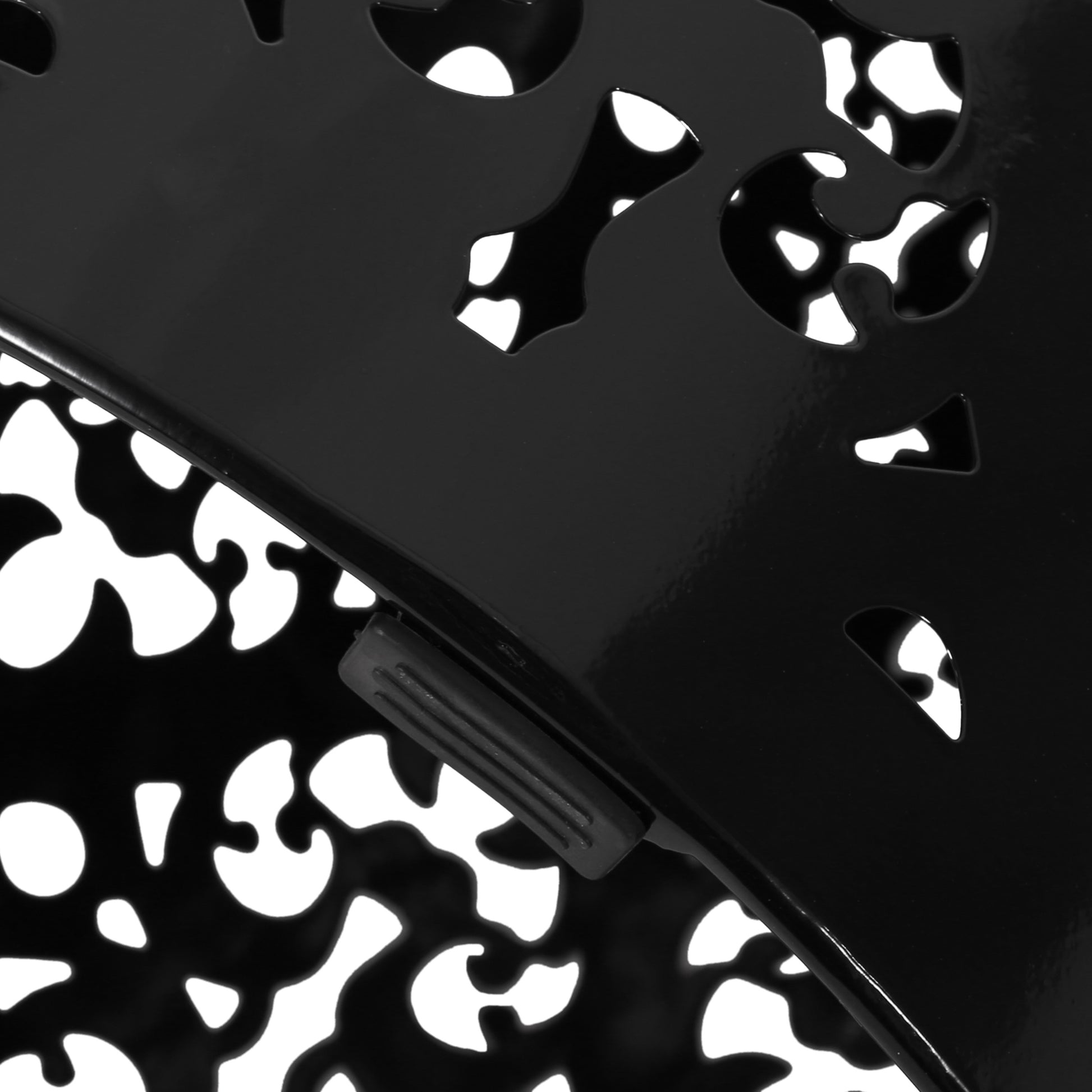 Closeup of a black metal lampshade with an intricate cutout pattern accentuating decorative lighting