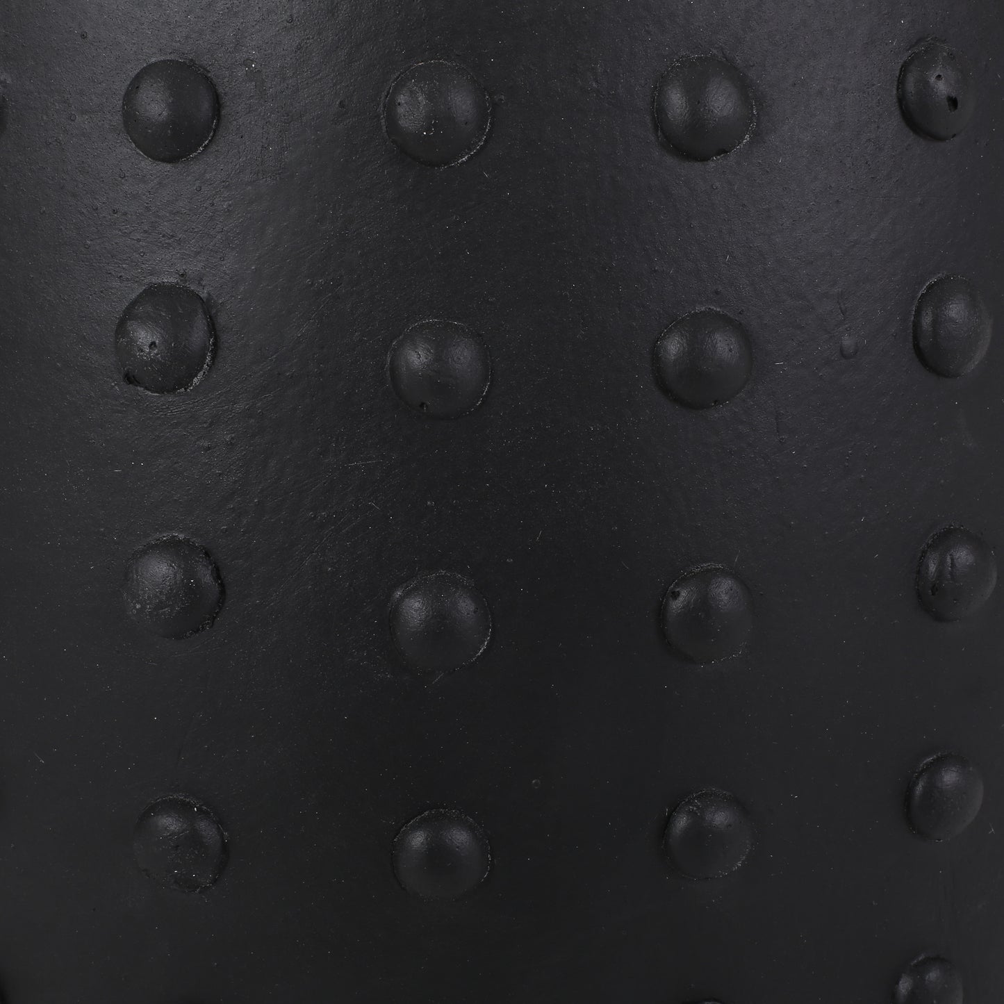 Closeup of a black rubber stress ball with raised circular bumps for grip