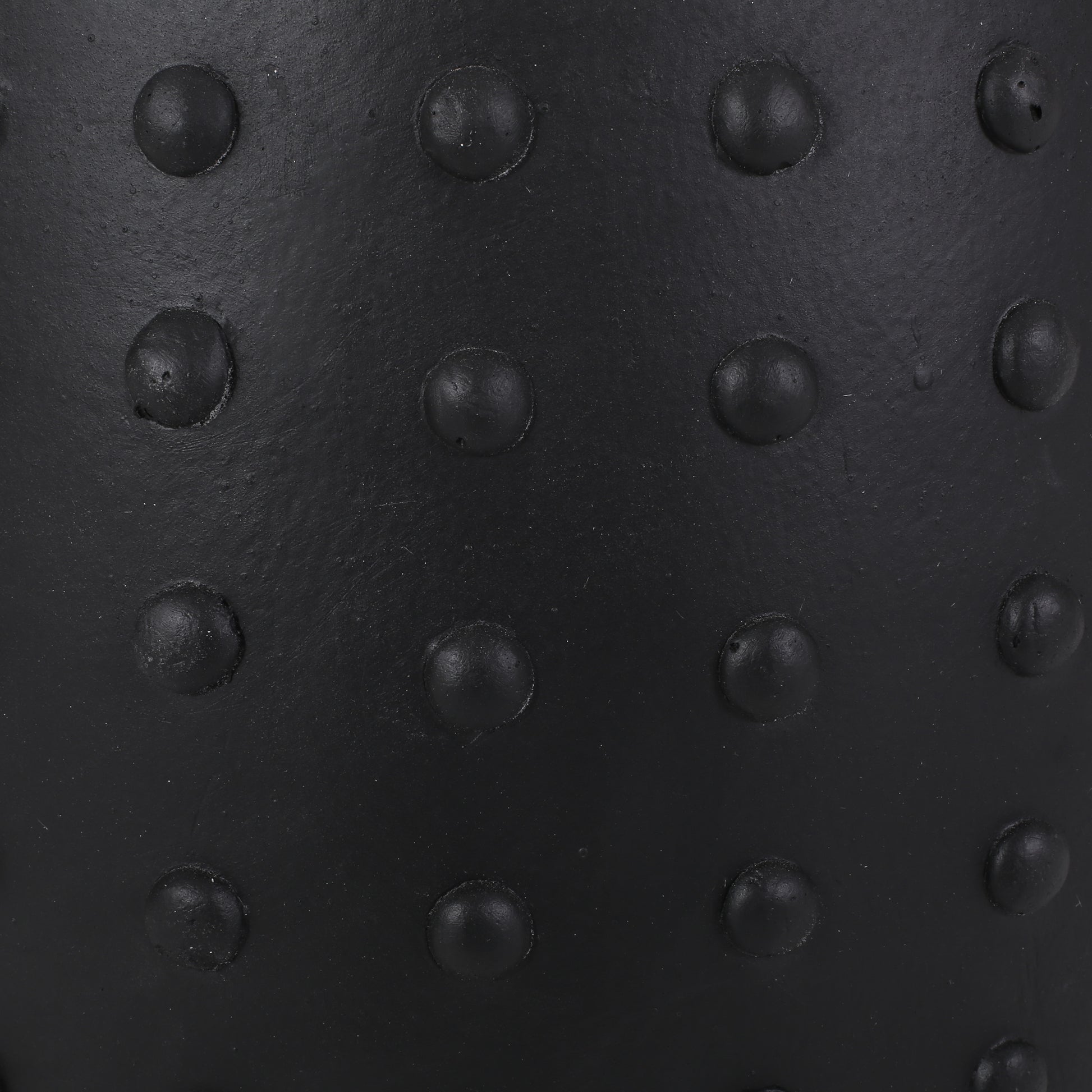 Closeup of a black rubber stress ball with raised circular bumps for grip