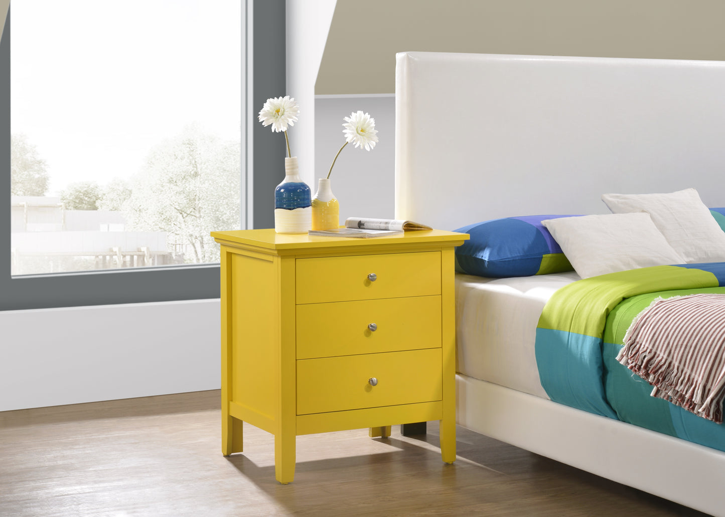 Bright yellow threedrawer wooden nightstand with silver knobs accenting a modern bedroom