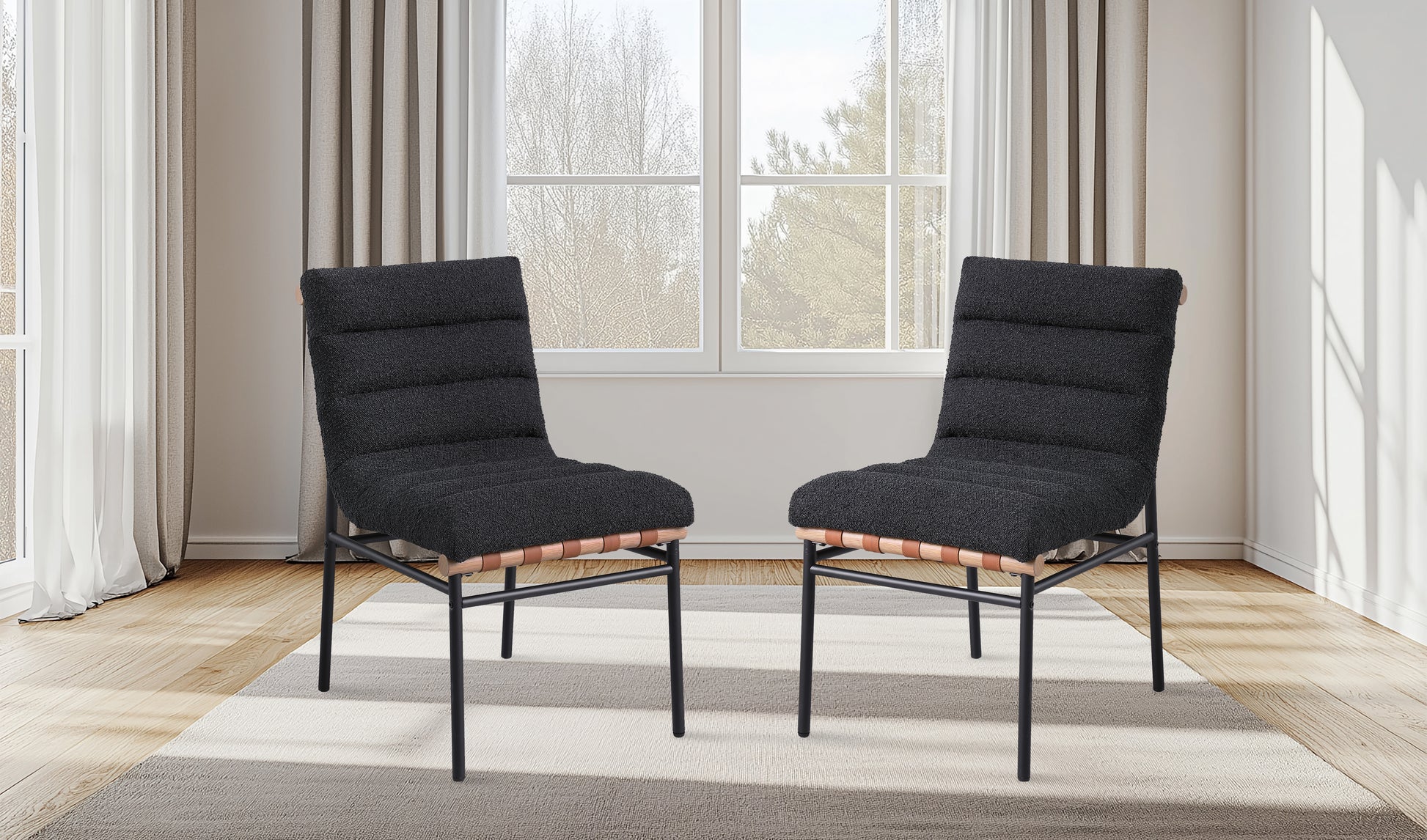 Two textured charcoal upholstered chairs with tan leather strap accents and black metal frames