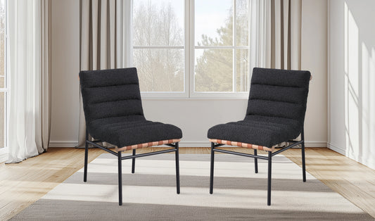 Two textured charcoal upholstered chairs with tan leather strap accents and black metal frames
