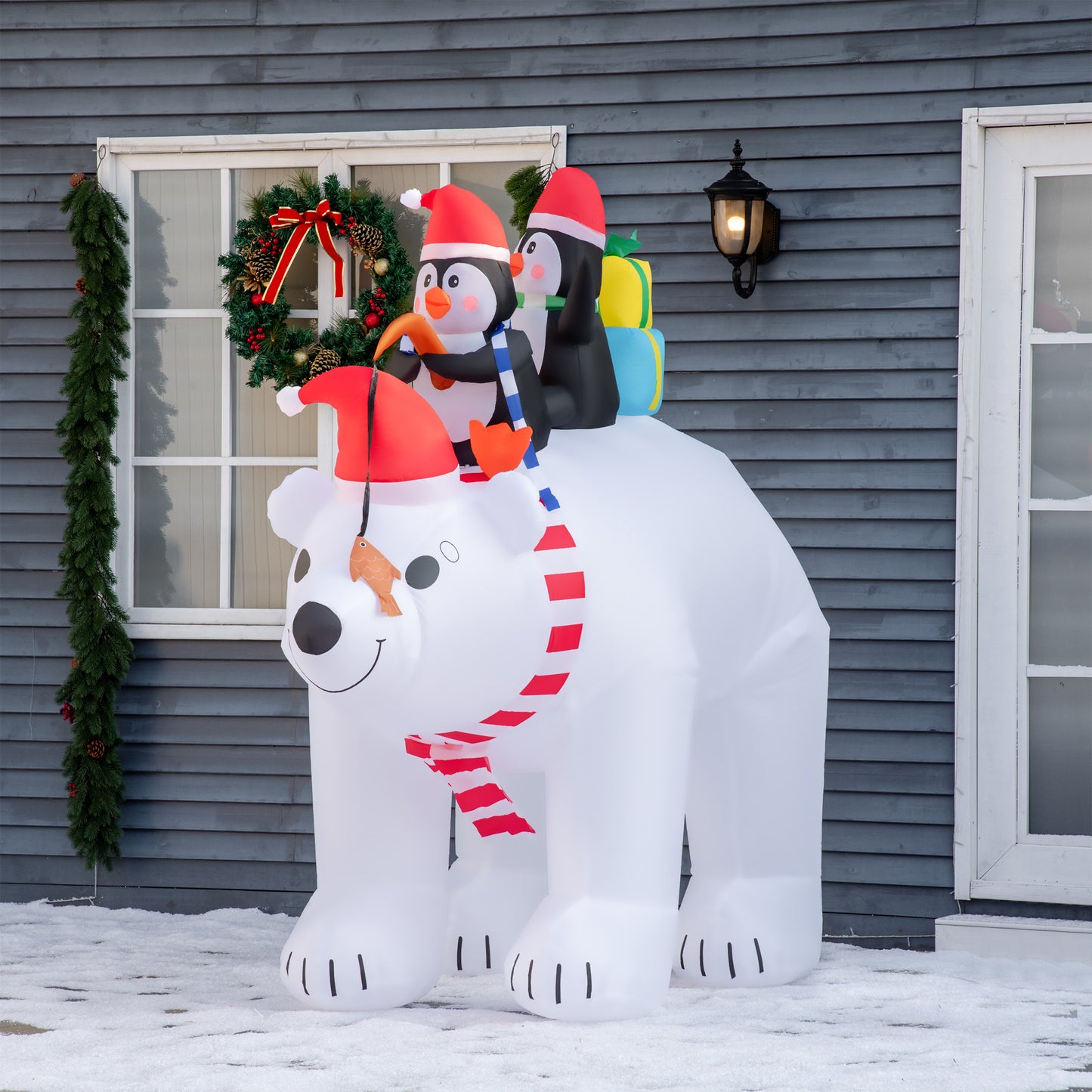 White inflatable polar bear with two penguins on its back wearing Santa hats Holiday decoration