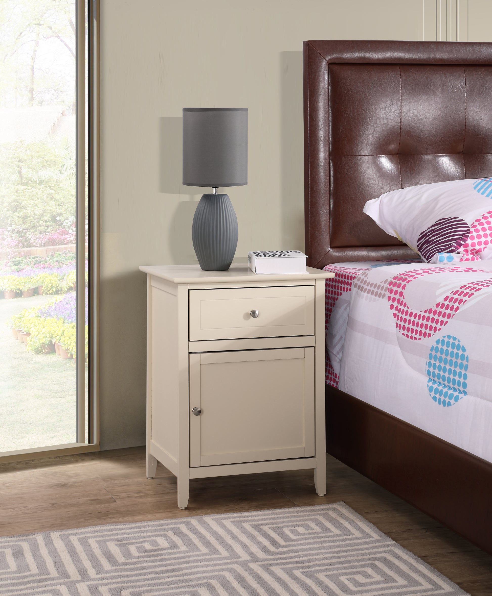 Cream wood nightstand with one drawer and cabinet next to a bed