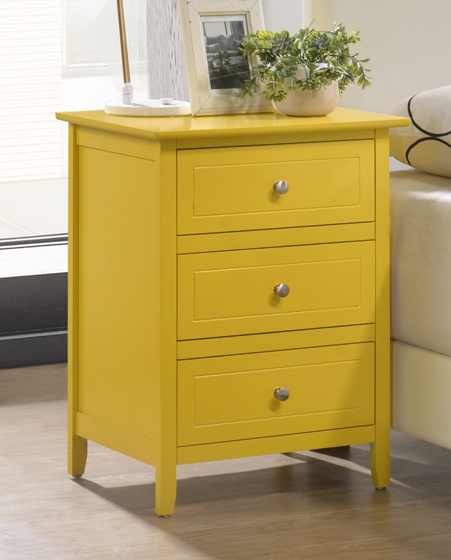 Yellow wooden nightstand with three drawers a perfect bedroom accent piece
