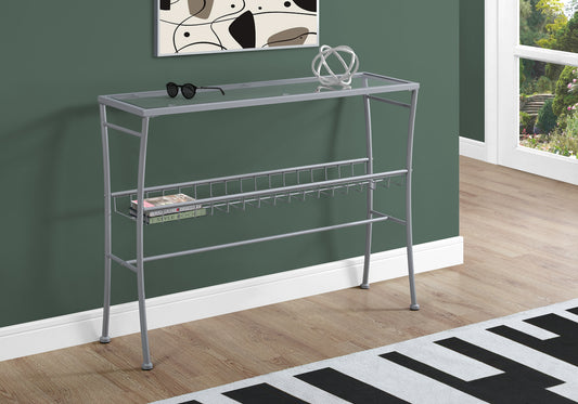 Sleek silver console table with glass top and wire magazine rack