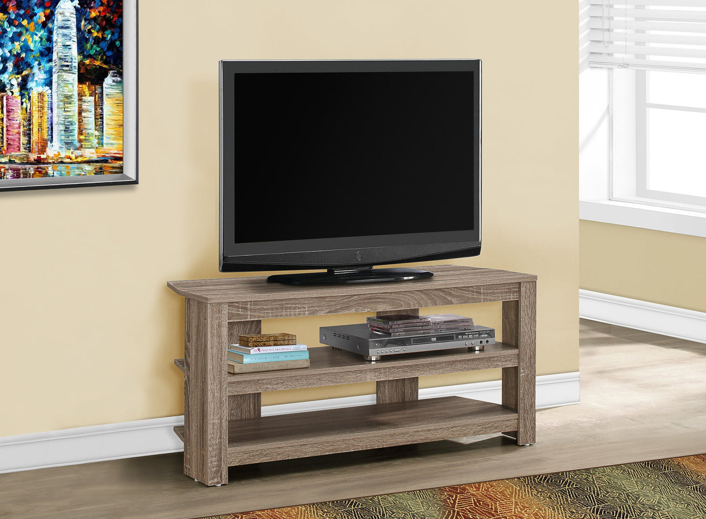 Modern grey wood TV stand with three shelves holding a television DVD player and books