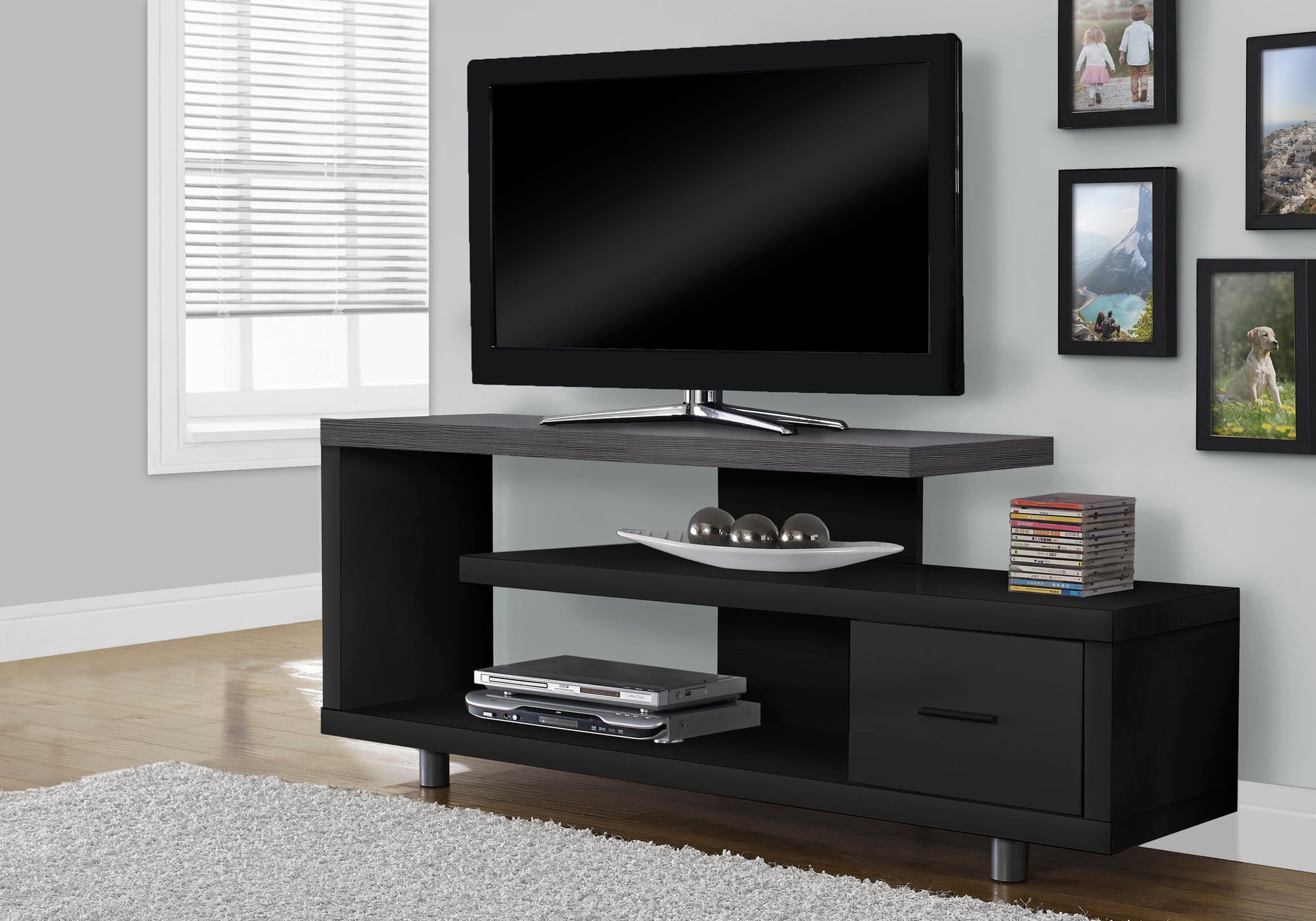 Modern black entertainment center with gray wood grain top shelf housing a flatscreen TV