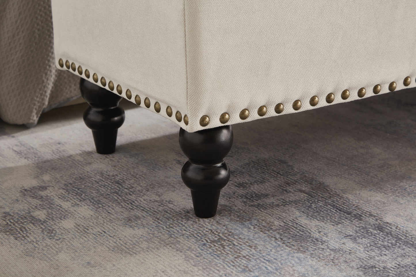 Cream upholstered ottoman with brass nailhead trim and dark wood legs