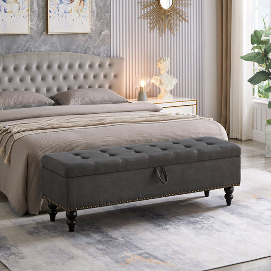 Dark grey tufted storage bench with brass nailhead trim and wooden legs