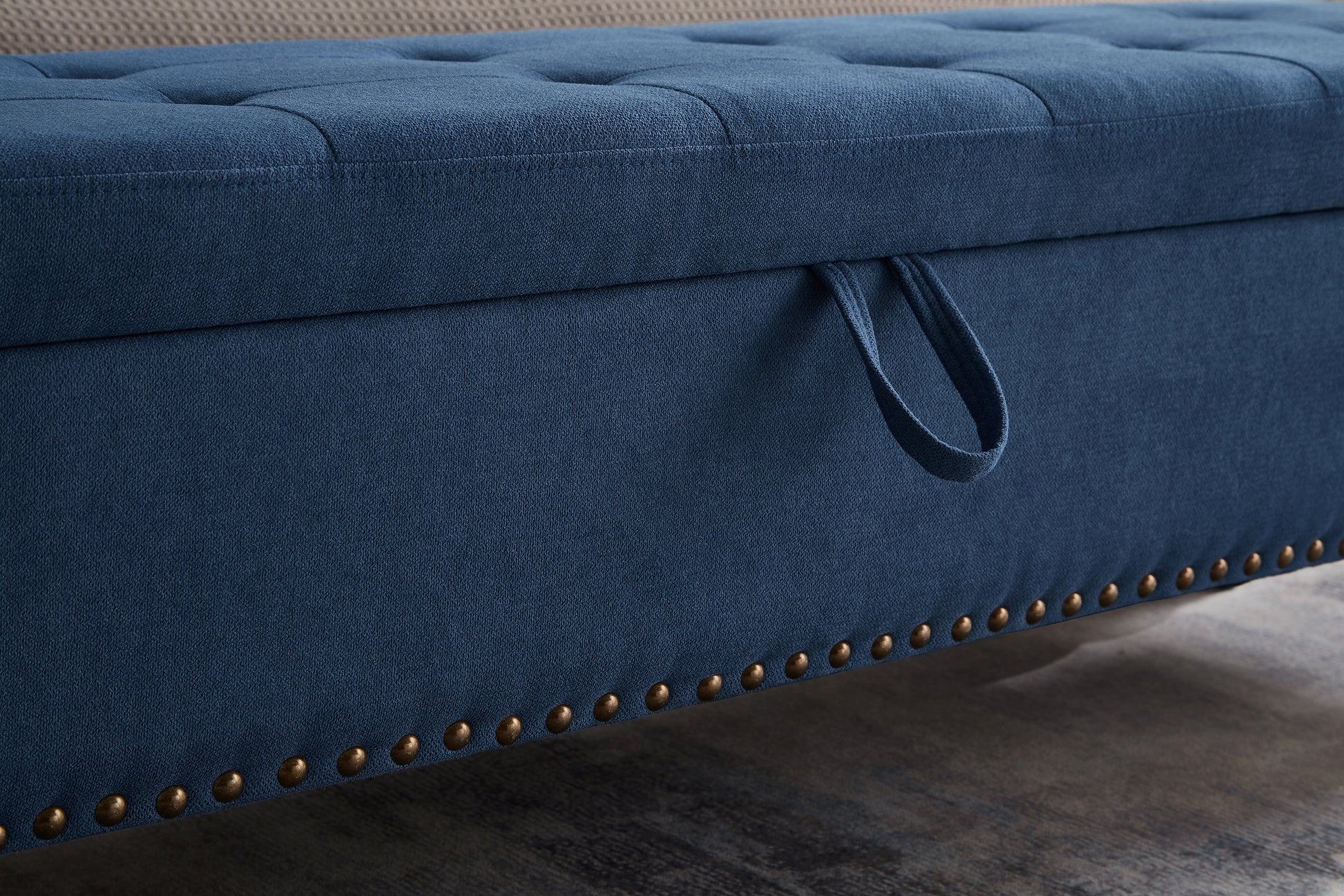 Navy blue storage ottoman with button tufting and brass nailhead trim