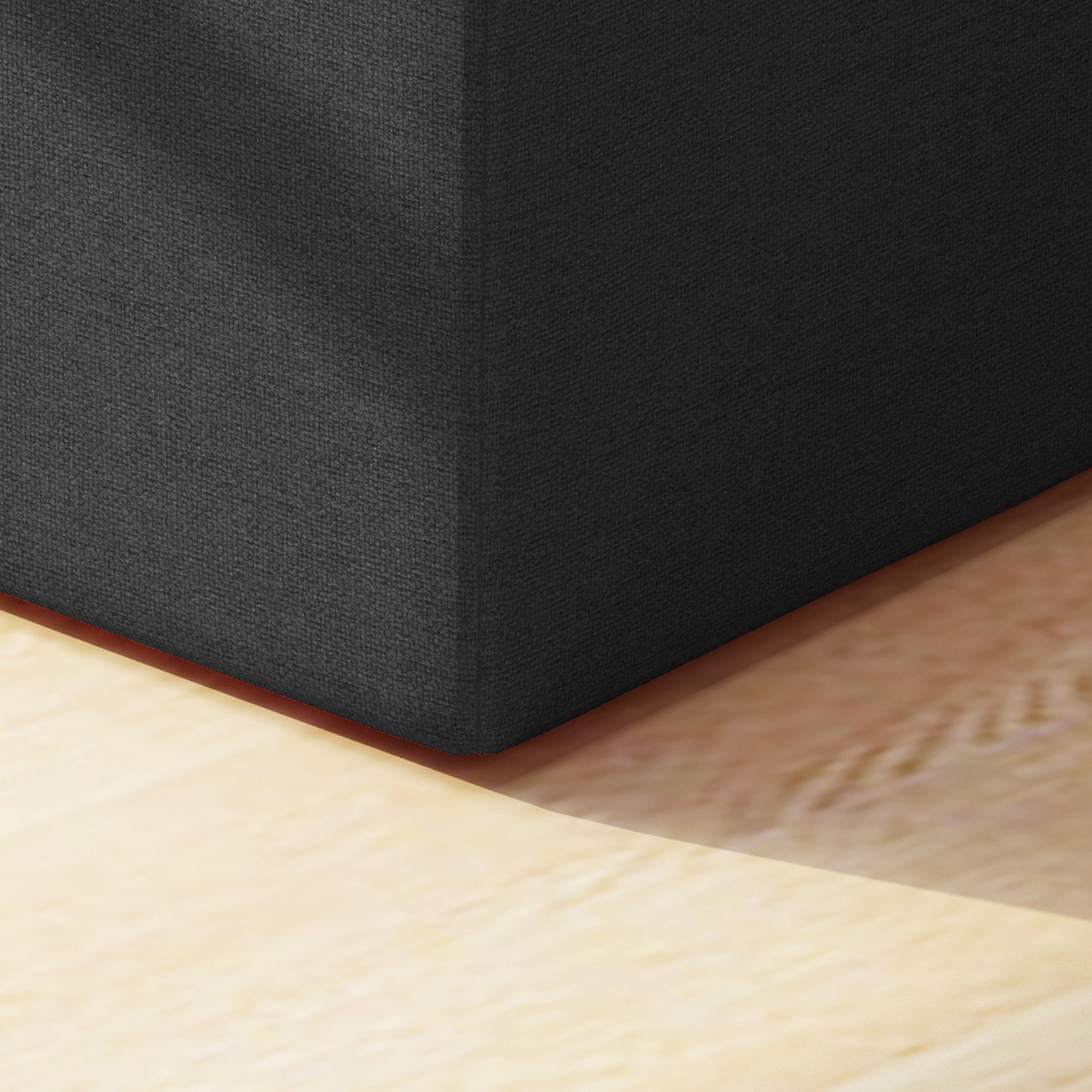 Dark gray textured ottoman corner on a light wood floor