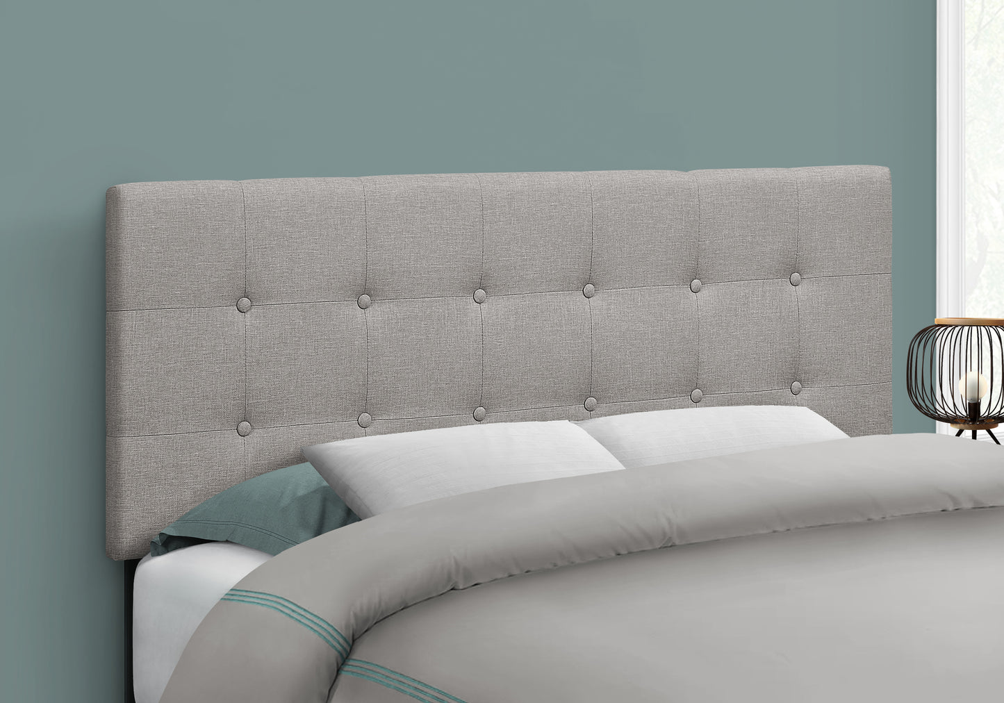 Light grey upholstered headboard with diamond tufting and silver buttons