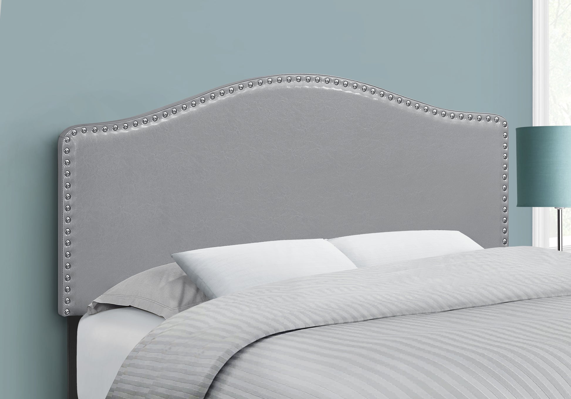 Gray upholstered headboard with silver nailhead trim showcasing curved top edge for a classic bed design