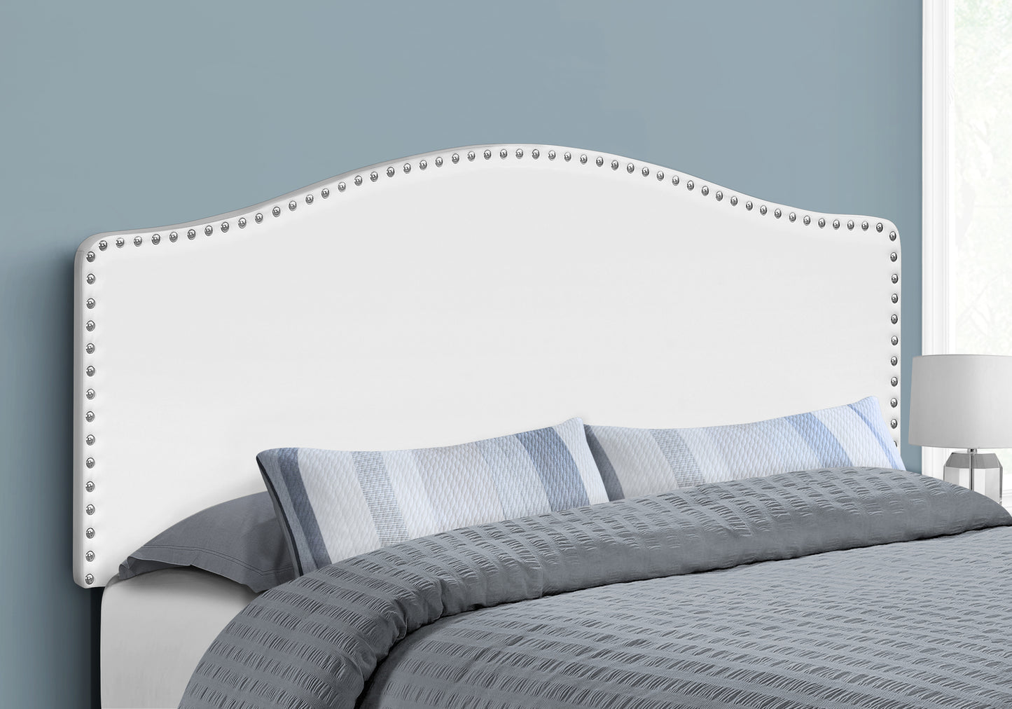 White upholstered headboard with silver nailhead trim complementing a modern bedroom