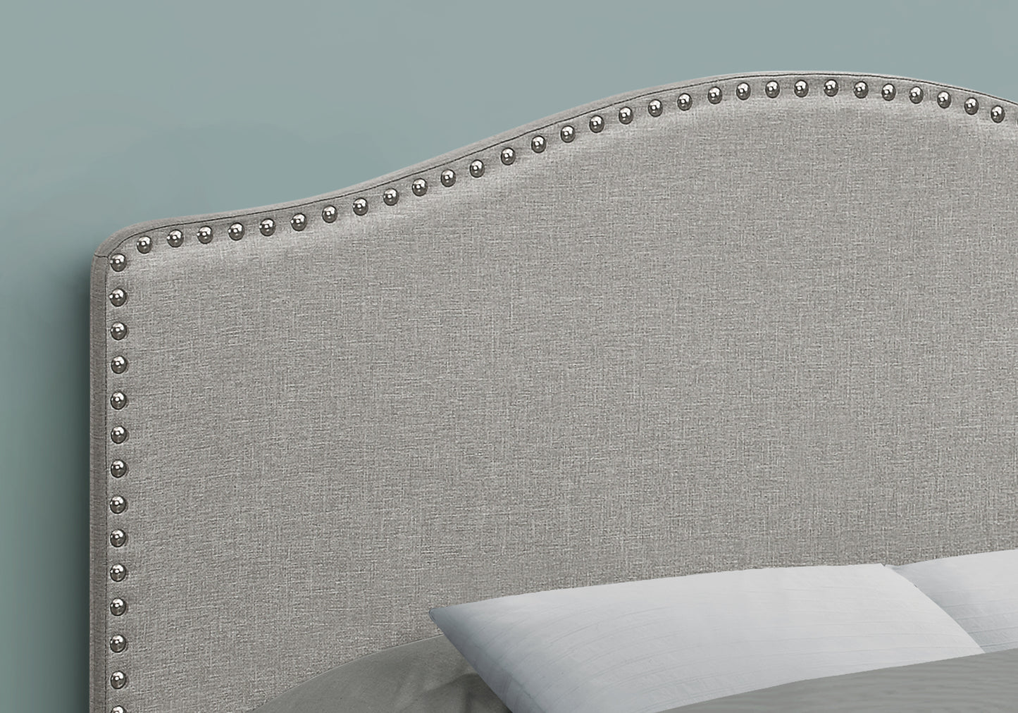 Grey fabric headboard with silver nailhead trim accents for a queen bed