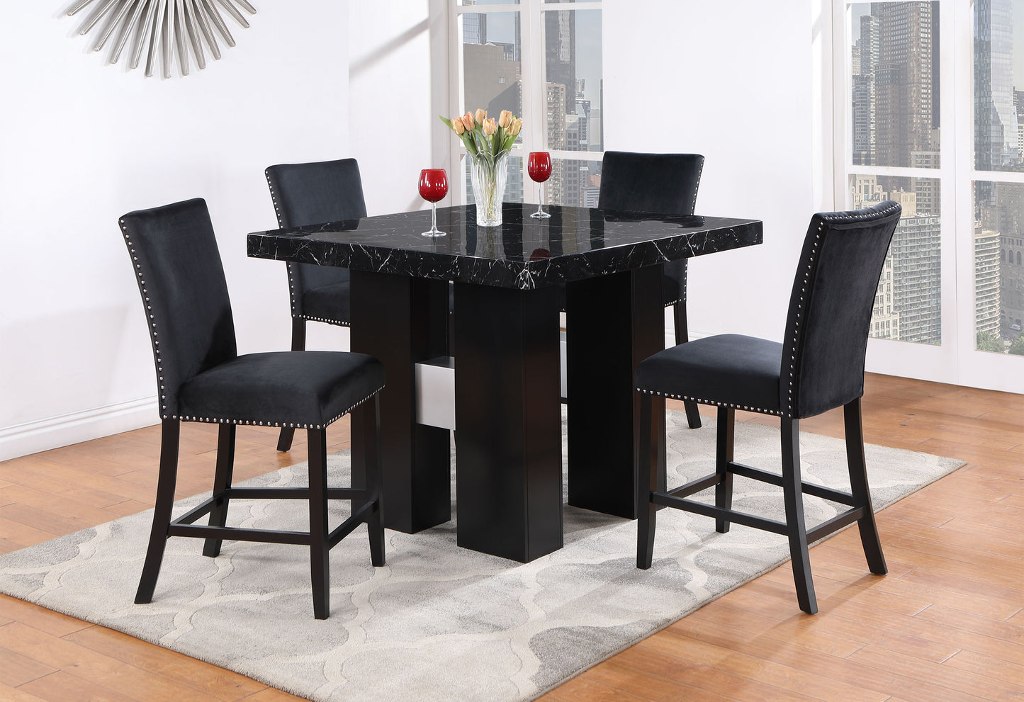 Four black velvet bar stools with nailhead trim surround a black marbletop pub table
