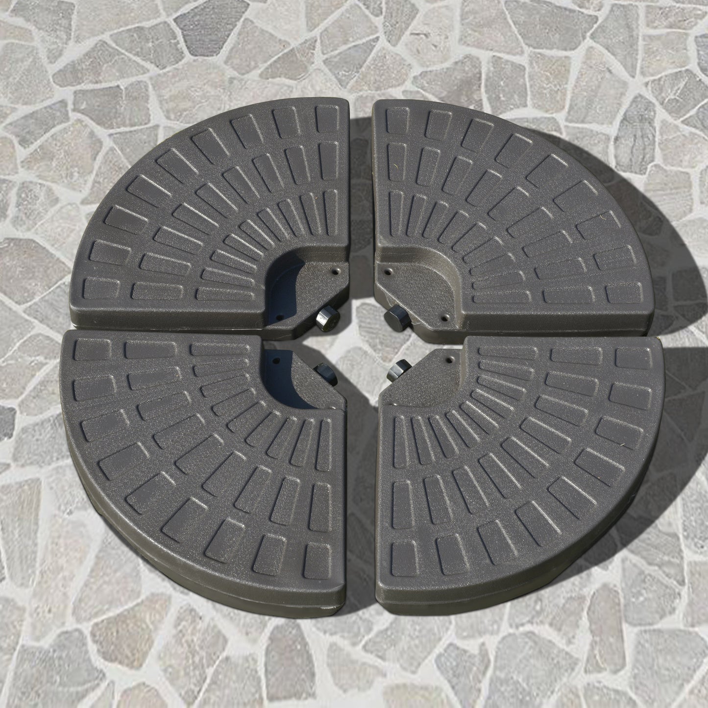 Four gray parasol base plates arranged in a circle on a stone patio creating a weighted stand