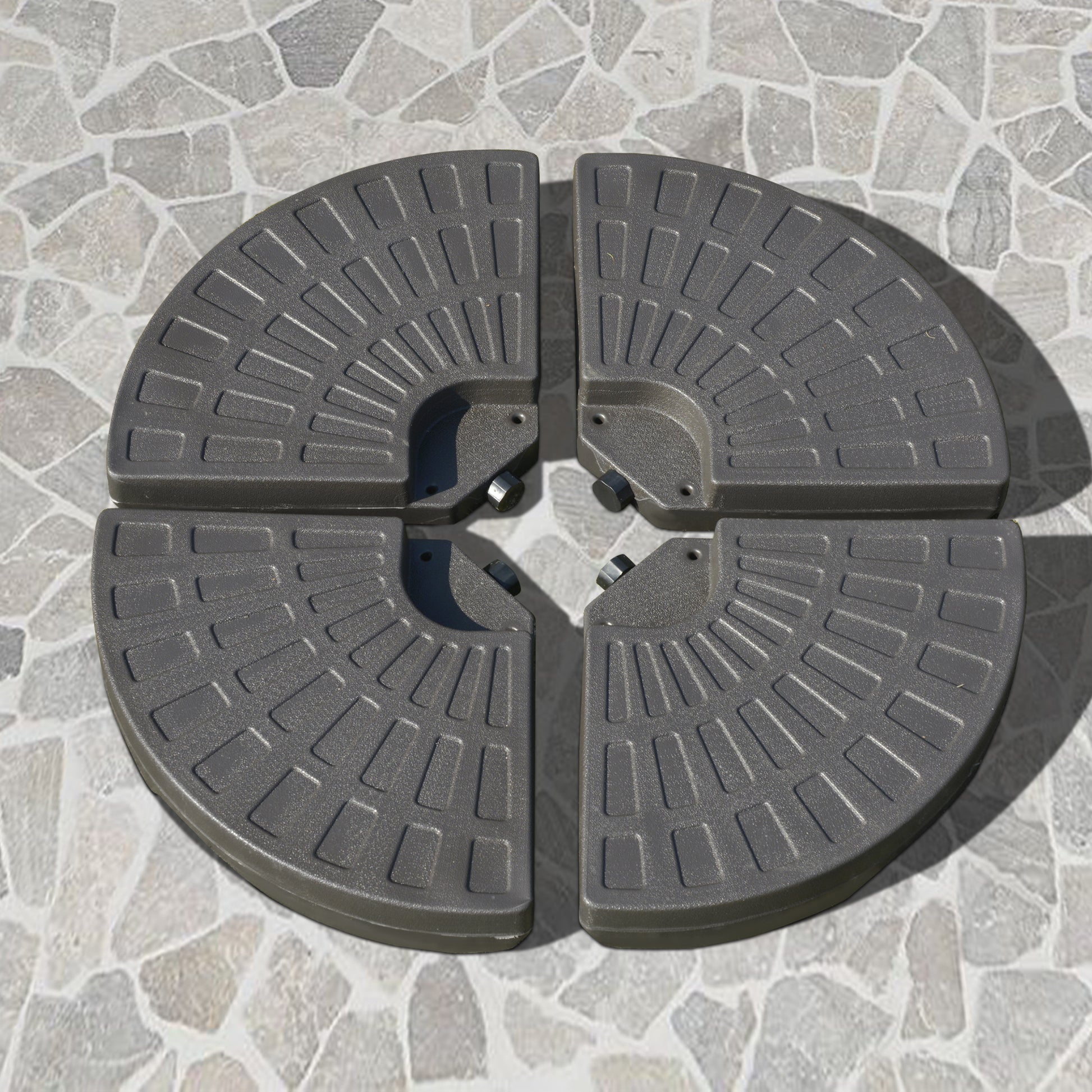 Four gray parasol base plates arranged in a circle on a stone patio creating a weighted stand