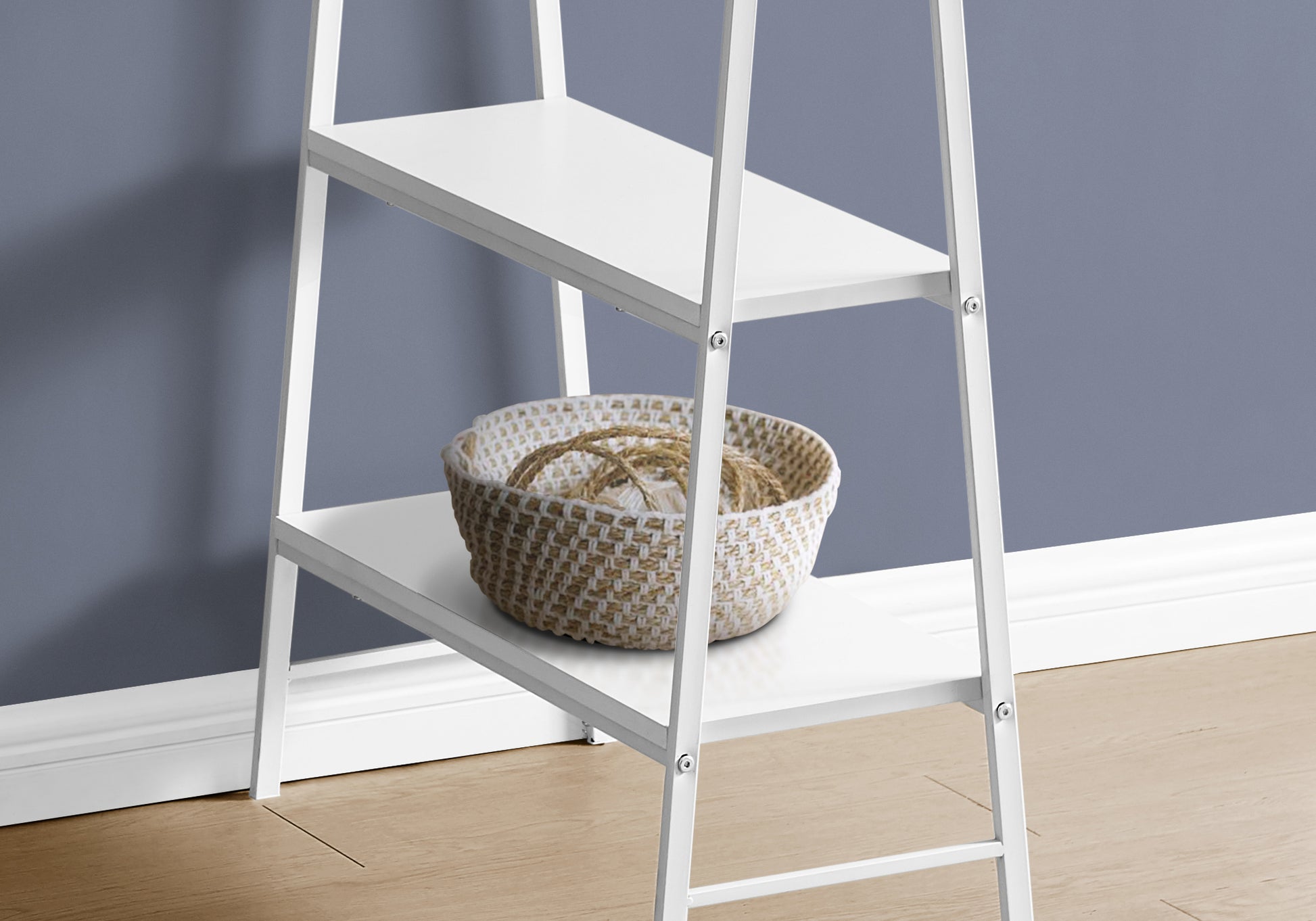 White metal tiered bookshelf with a woven basket on the second shelf