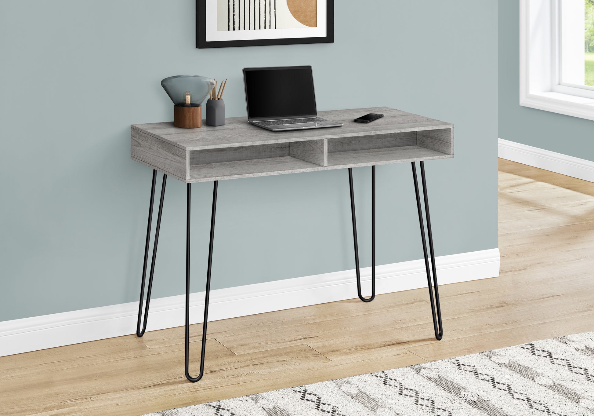 Grey wood desk with black hairpin legs featuring a laptop and phone for a modern home office
